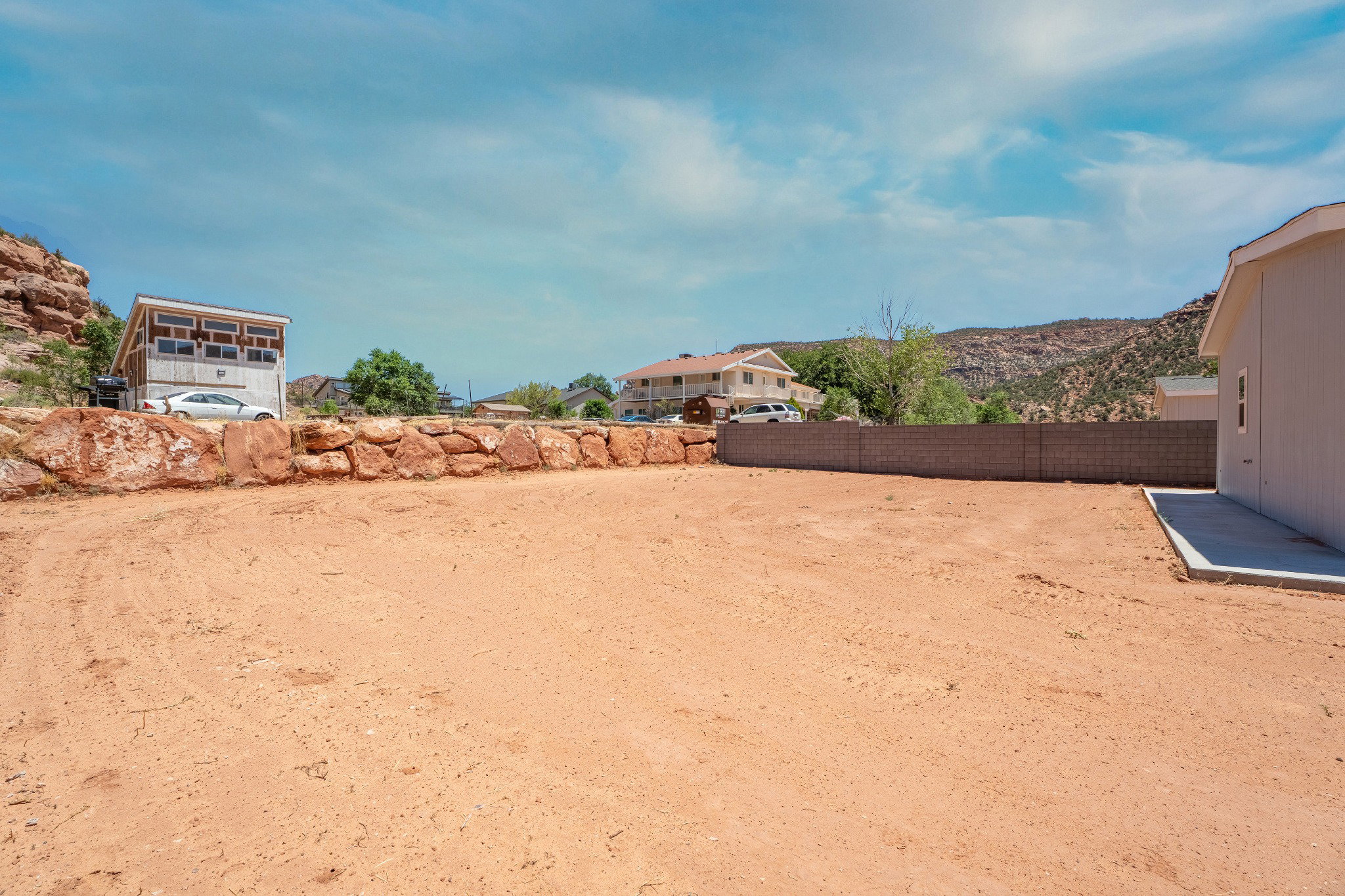 Generous lot cleared and prepared for development, featuring a natural stone retaining wall, a sturdy block wall, and a concrete pad
