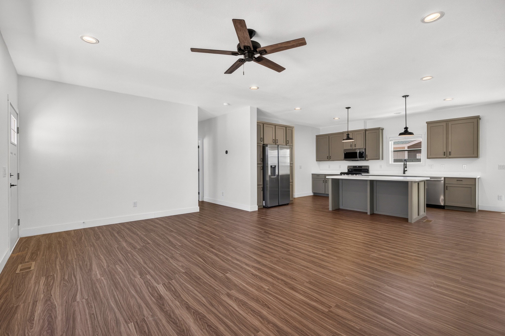 Open-concept living space featuring wood-finish flooring, recessed lighting, and a dark-toned ceiling fan