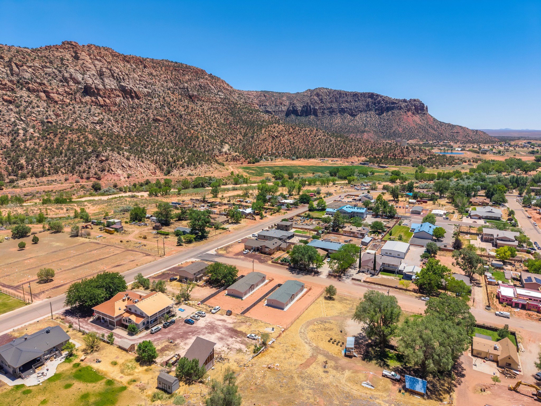 Expansive aerial capturing a rural community bordered by prominent red rock formations