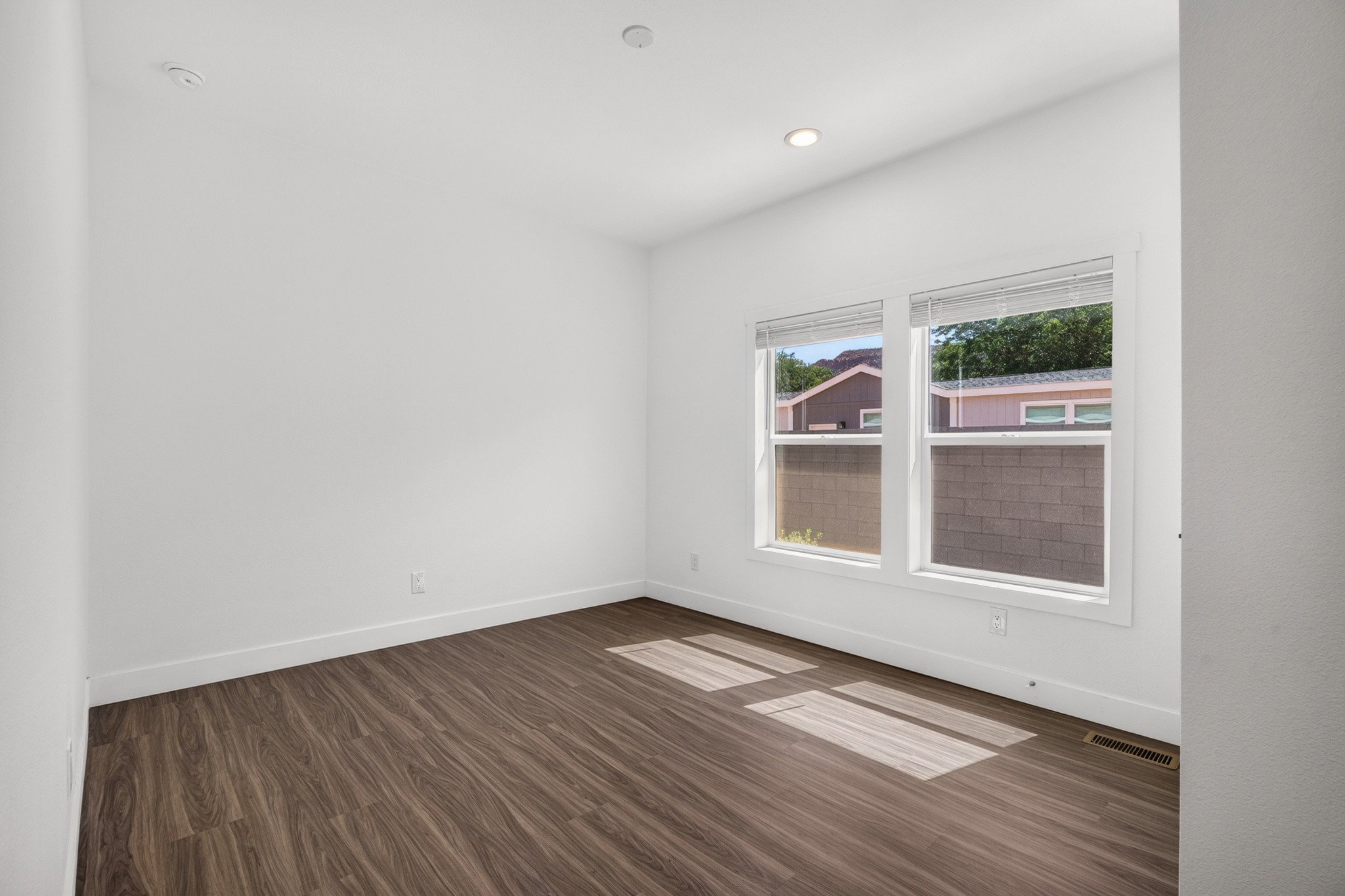 Interior space featuring wood-finish flooring, white baseboards, and bright white walls
