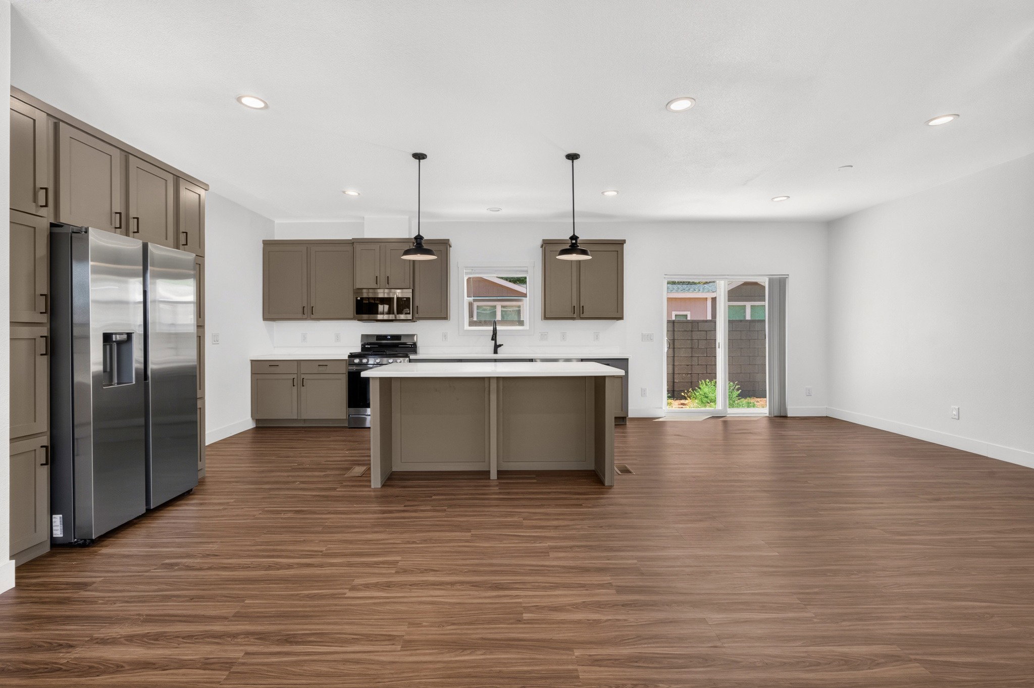 Open-concept kitchen and living area featuring wood-finish flooring, recessed lighting, and a sliding glass door