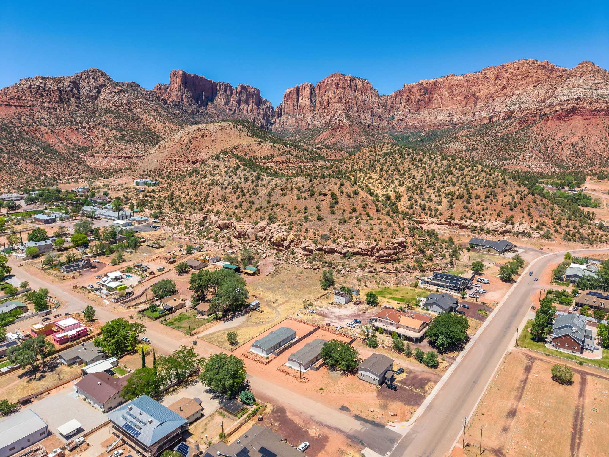 Aerial perspective showcasing a community nestled against a red rock mountain range under a clear sky