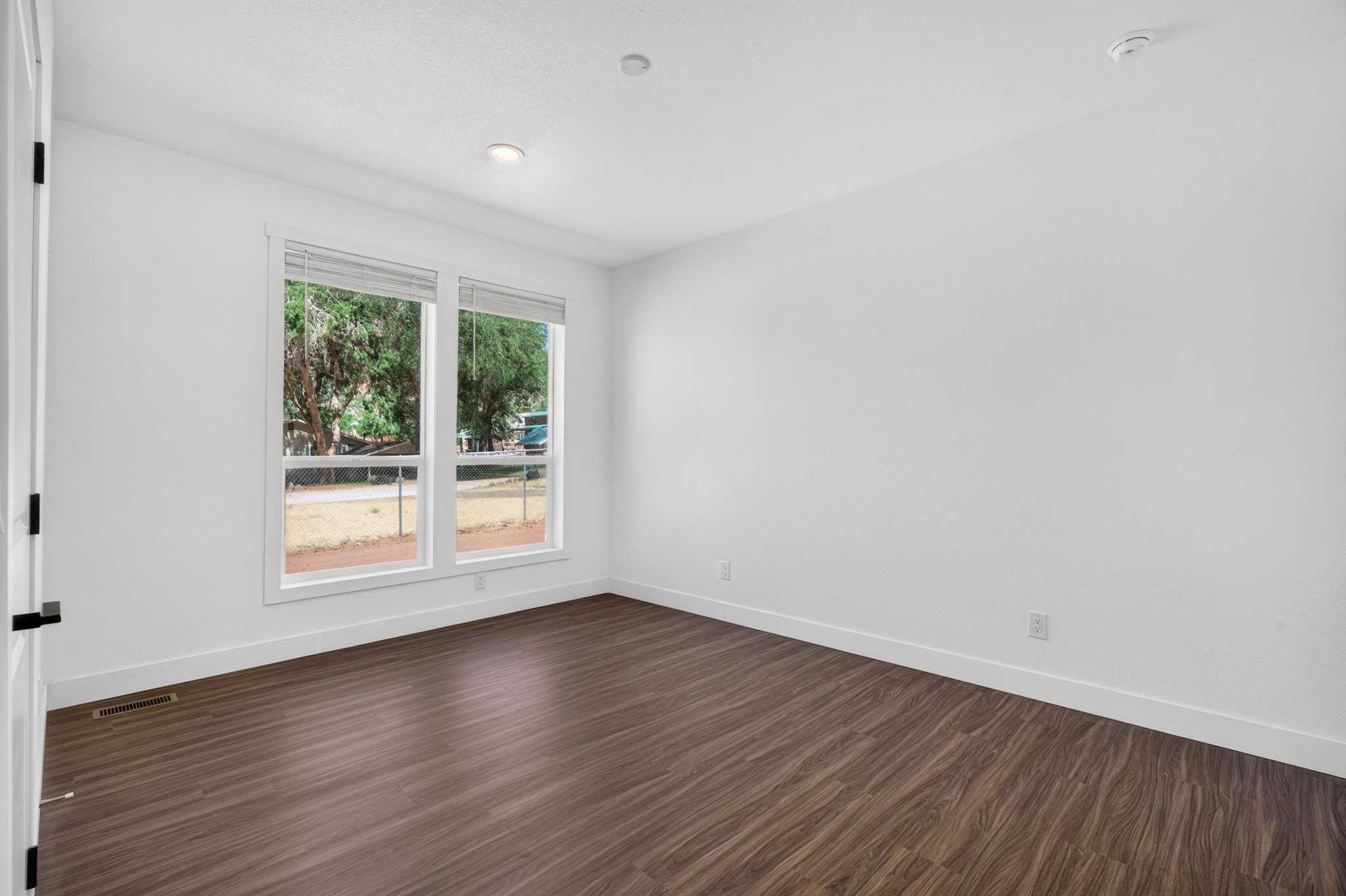 Bright room featuring wood-finish flooring, white walls, and white trim