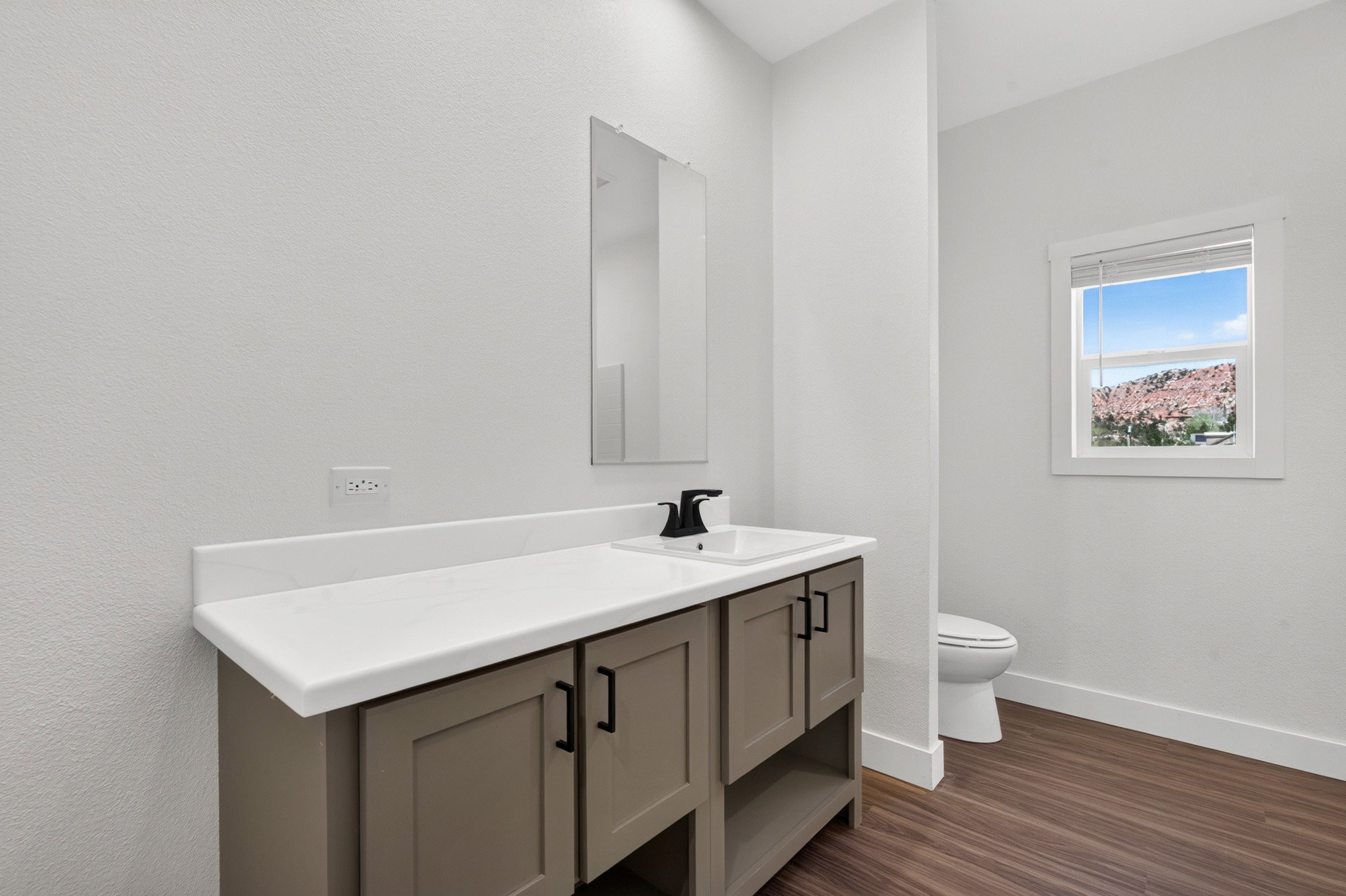 Bathroom featuring a single vanity with a white countertop, rectangular sink, and matte black faucet