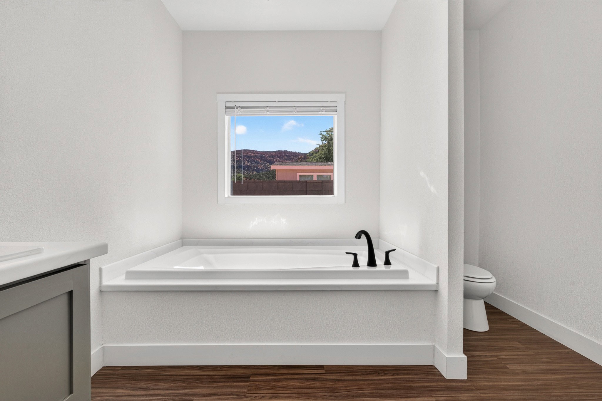 Built-in soaking tub with matte black fixtures and a surrounding white countertop