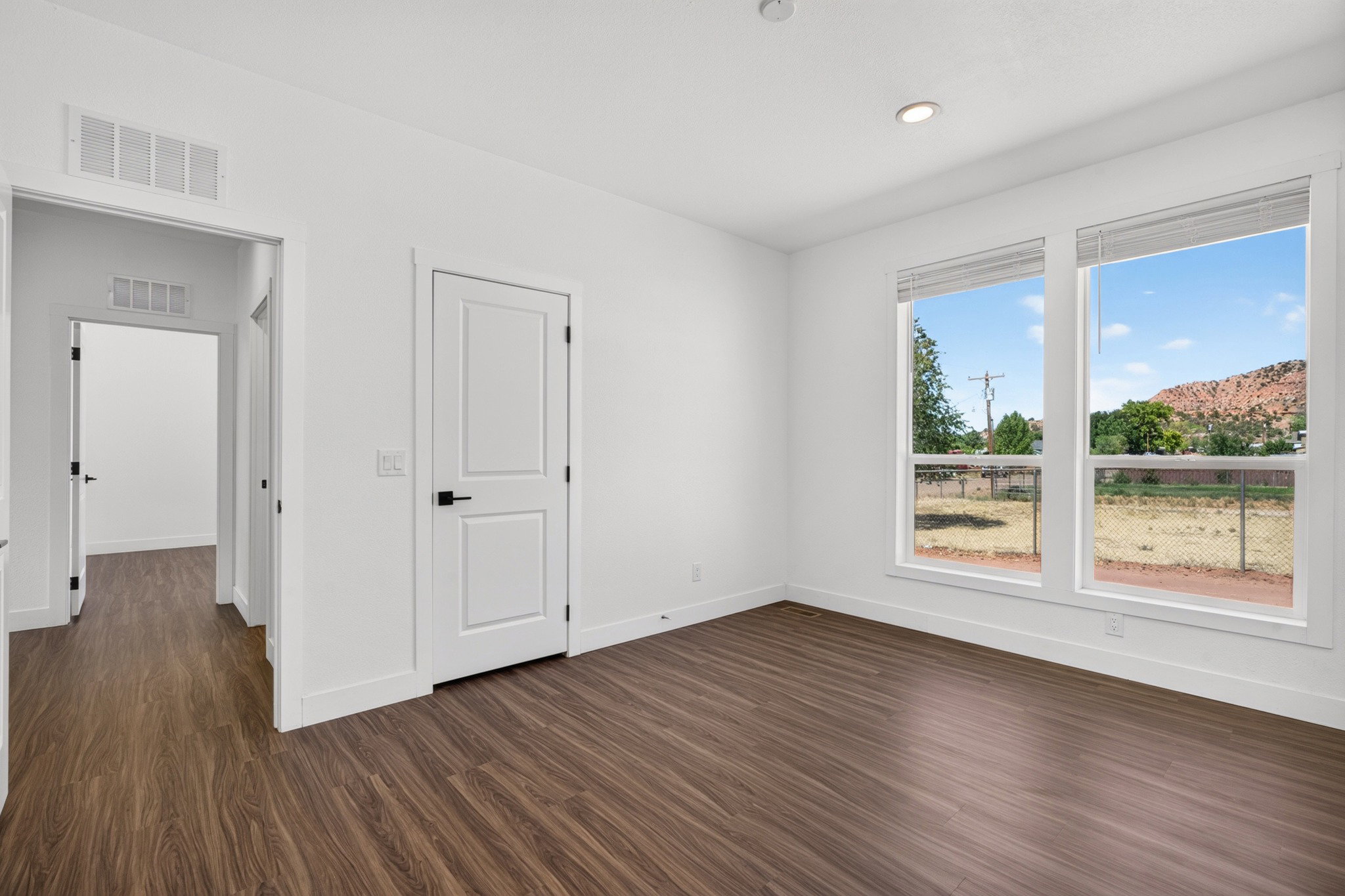 Bright interior space featuring wood-finish flooring, white walls, and contemporary doors with matte black hardware