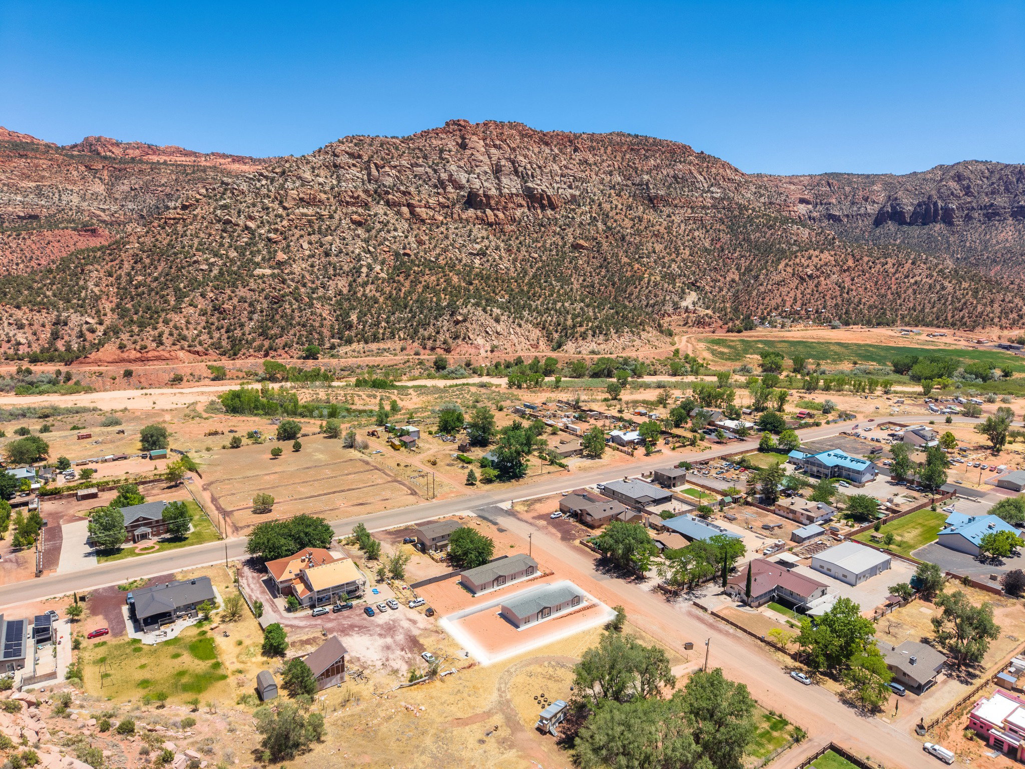 Aerial perspective showcasing a residential community nestled against a backdrop of red rock mountains and green vegetation