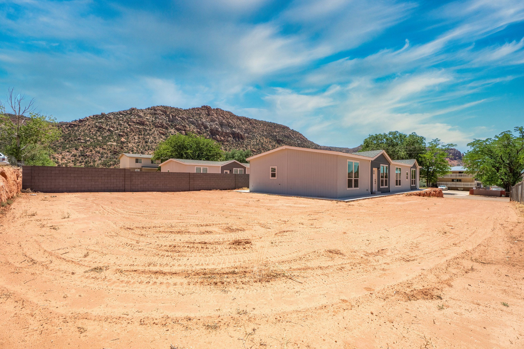 Expansive lot featuring a newly constructed residence with a gray facade, dark trim, and multiple windows