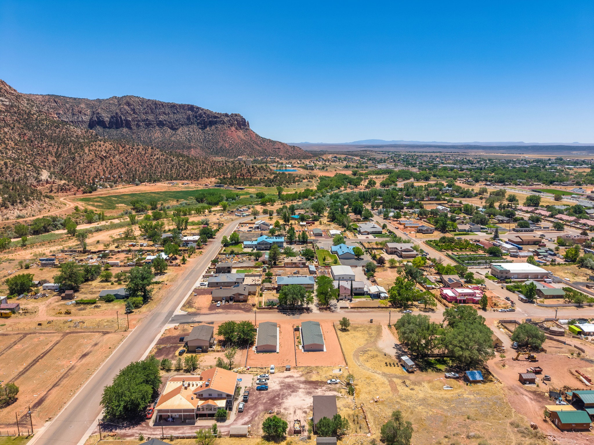 Expansive aerial perspective showcasing a rural community with varied residential and commercial structures, bordered by a prominent mountain range