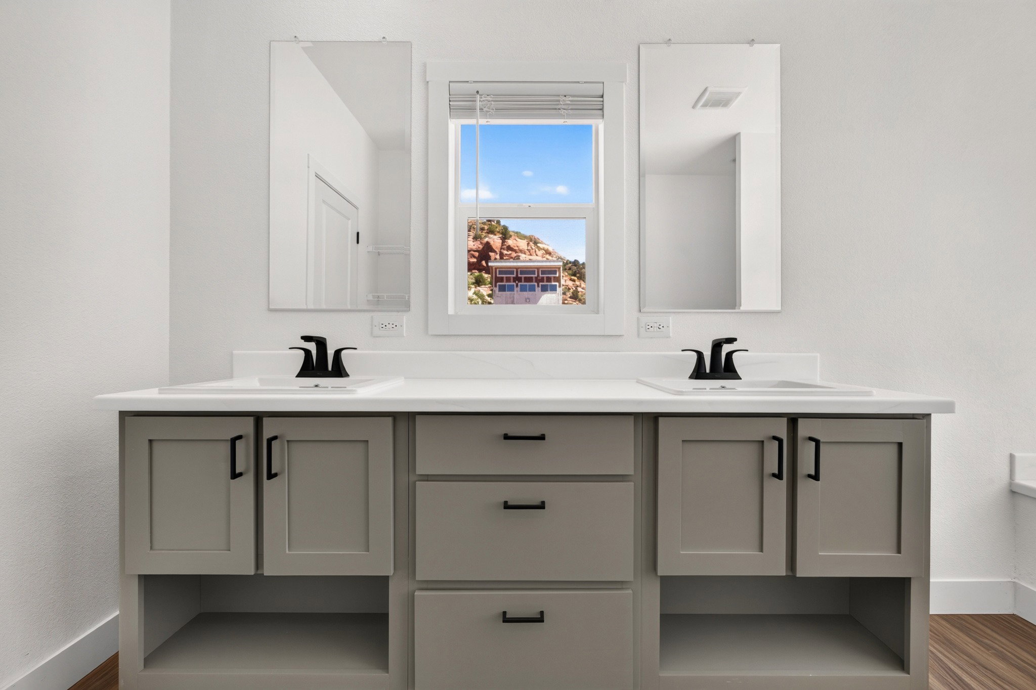 Double vanity with dual sinks, matte black faucets, and light gray cabinetry featuring black hardware