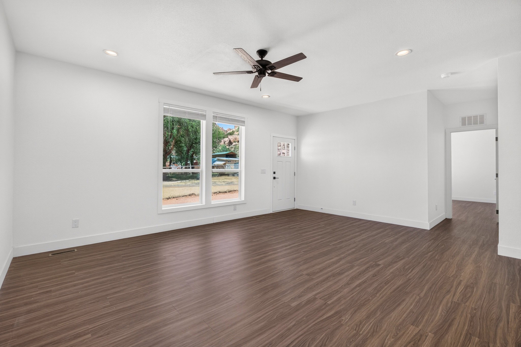 Spacious room featuring wood-finish flooring, white walls, and recessed lighting
