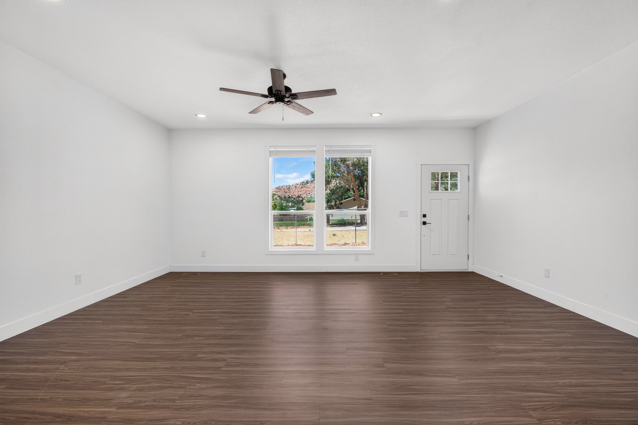 Spacious open-concept room featuring wood-finish flooring, recessed lighting, and a ceiling fan