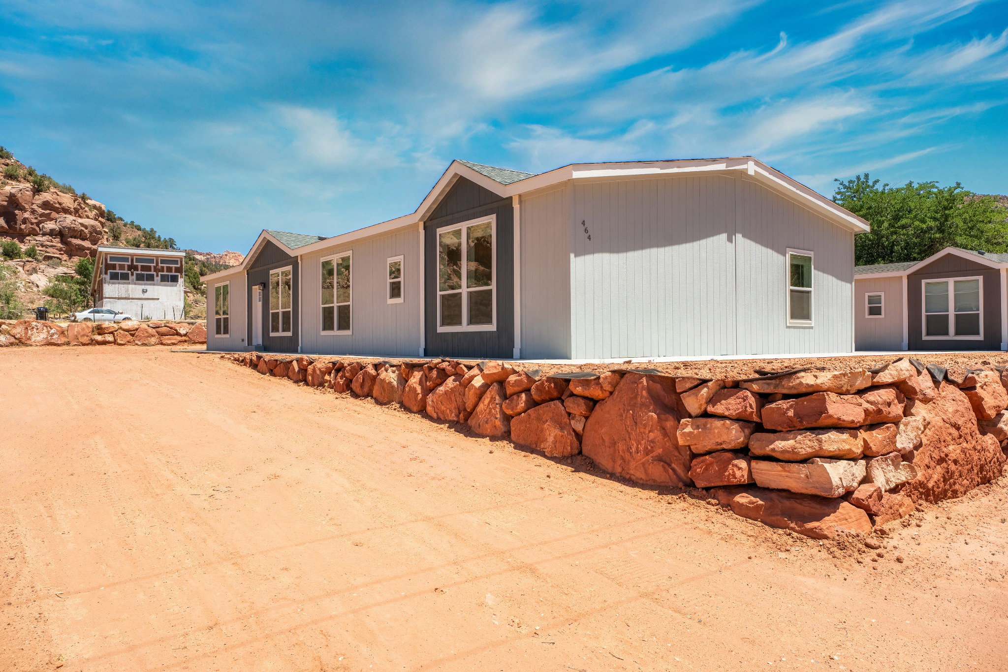 Modern manufactured home featuring light gray vertical siding and dark gray gable accents
