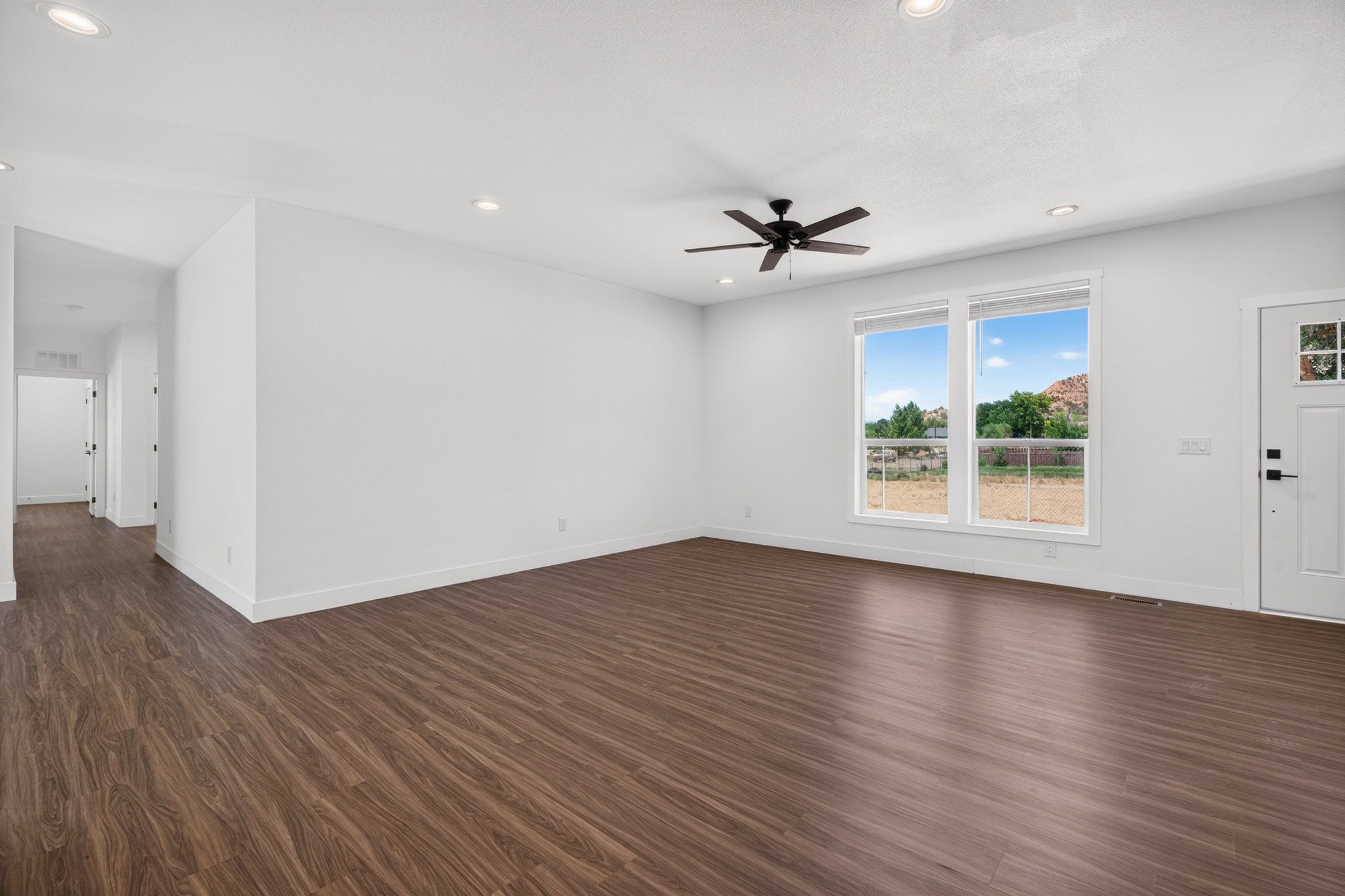 Spacious living area featuring wood-finish flooring, white walls, and recessed lighting