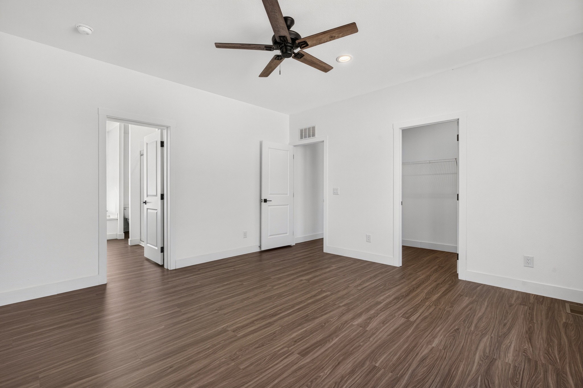Spacious room featuring wood-finish flooring, a contemporary ceiling fan, recessed lighting, and a walk-in closet with wire shelving