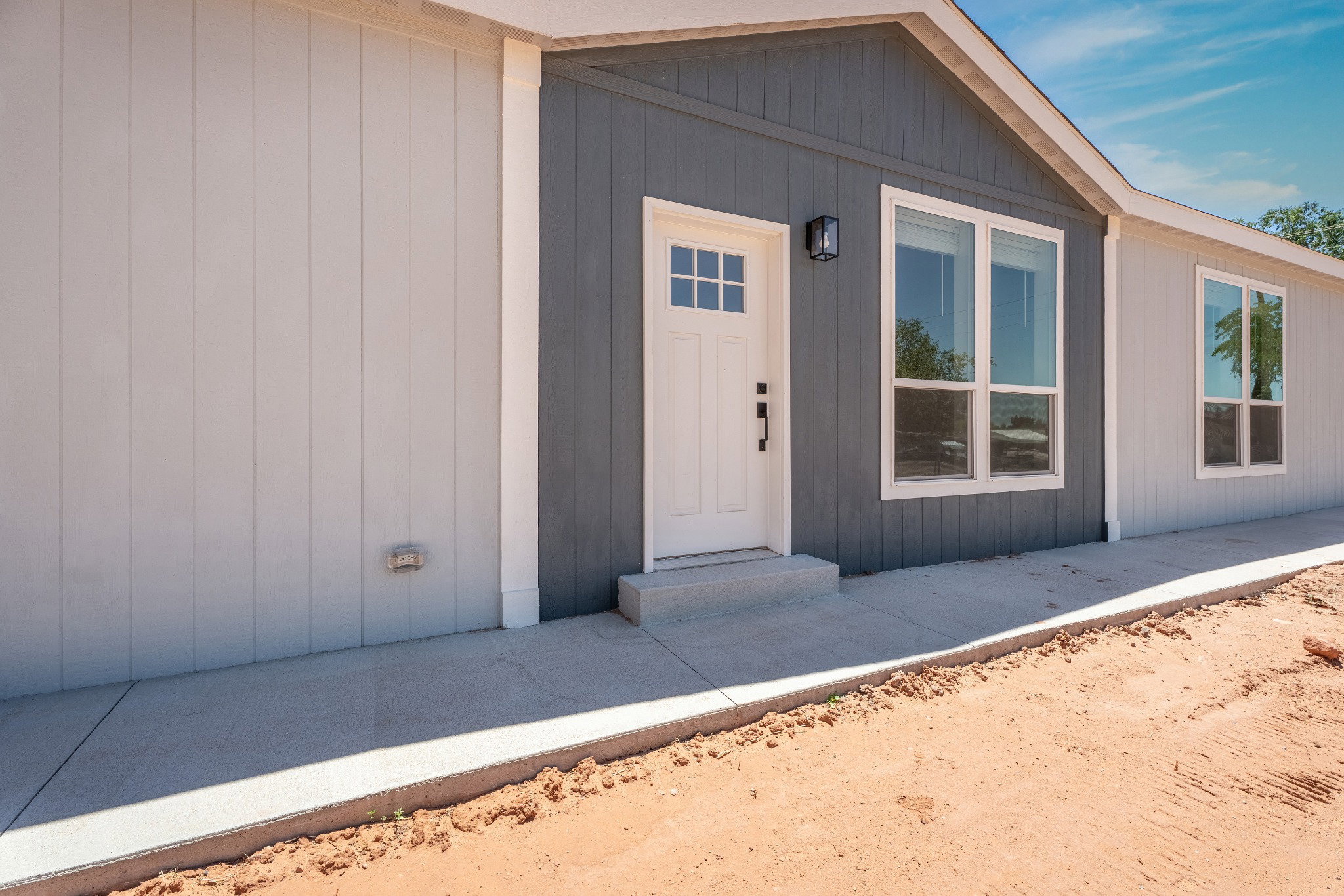 Modern home exterior featuring a white paneled door with window accents, an overhead black lantern-style light fixture, and white-framed windows