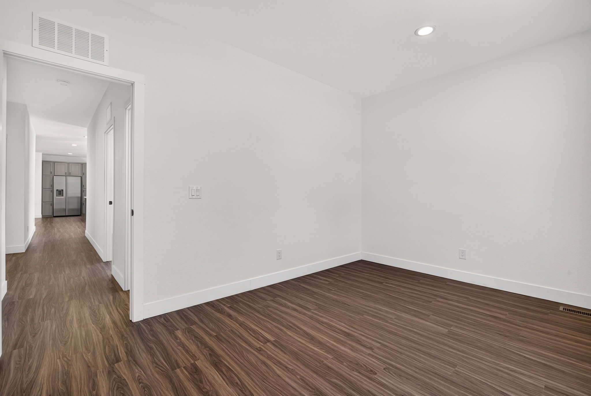 Spacious room featuring wood-finish flooring, white baseboards, and neutral wall tones