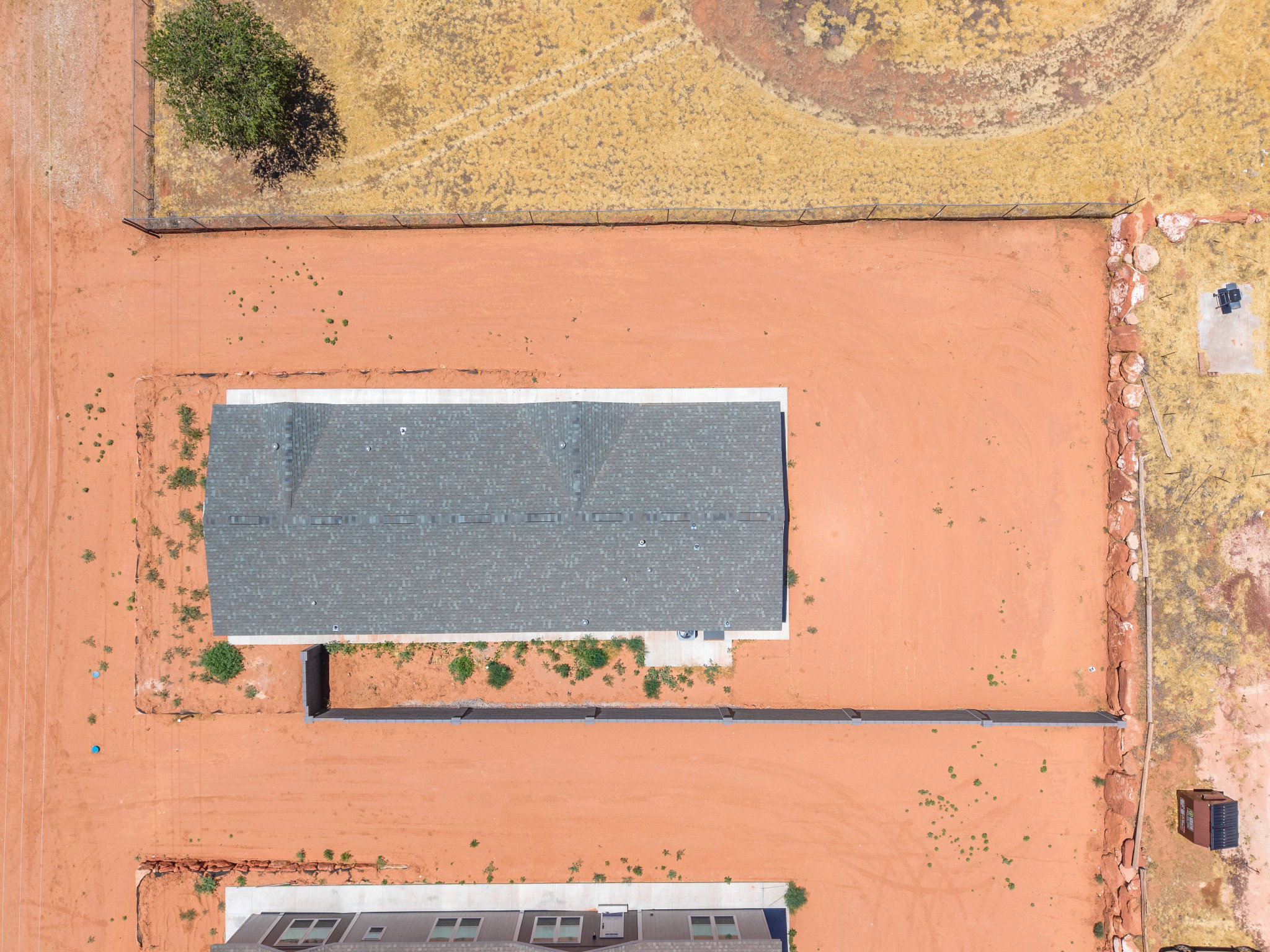 New construction featuring a gray shingle roof and surrounding cleared land