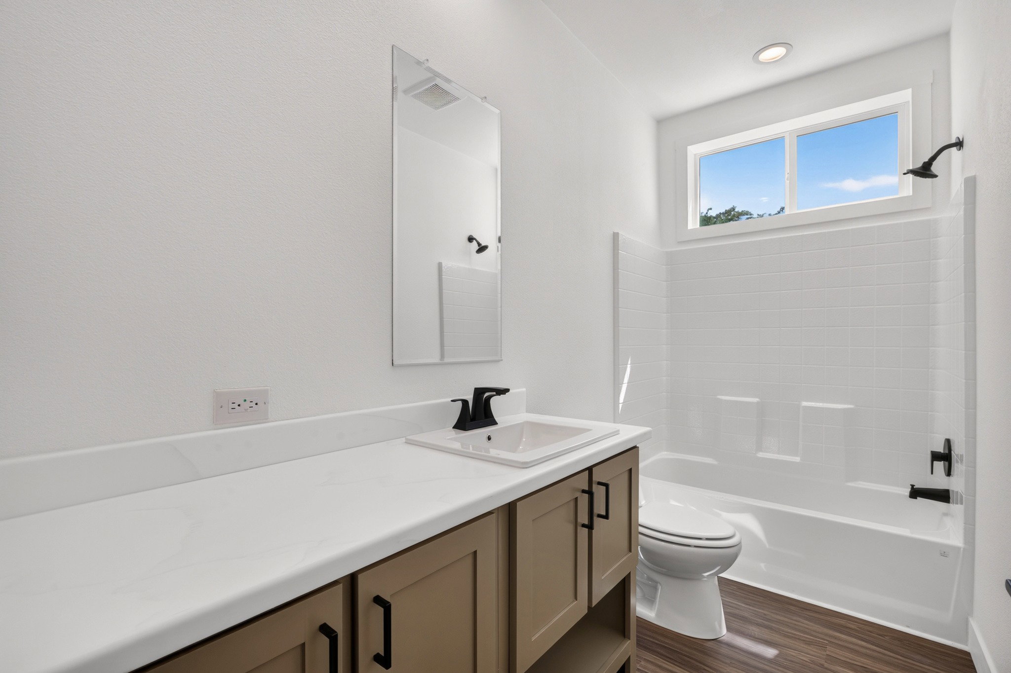 Contemporary bathroom featuring a vanity with brown cabinetry, white countertop, and integrated sink