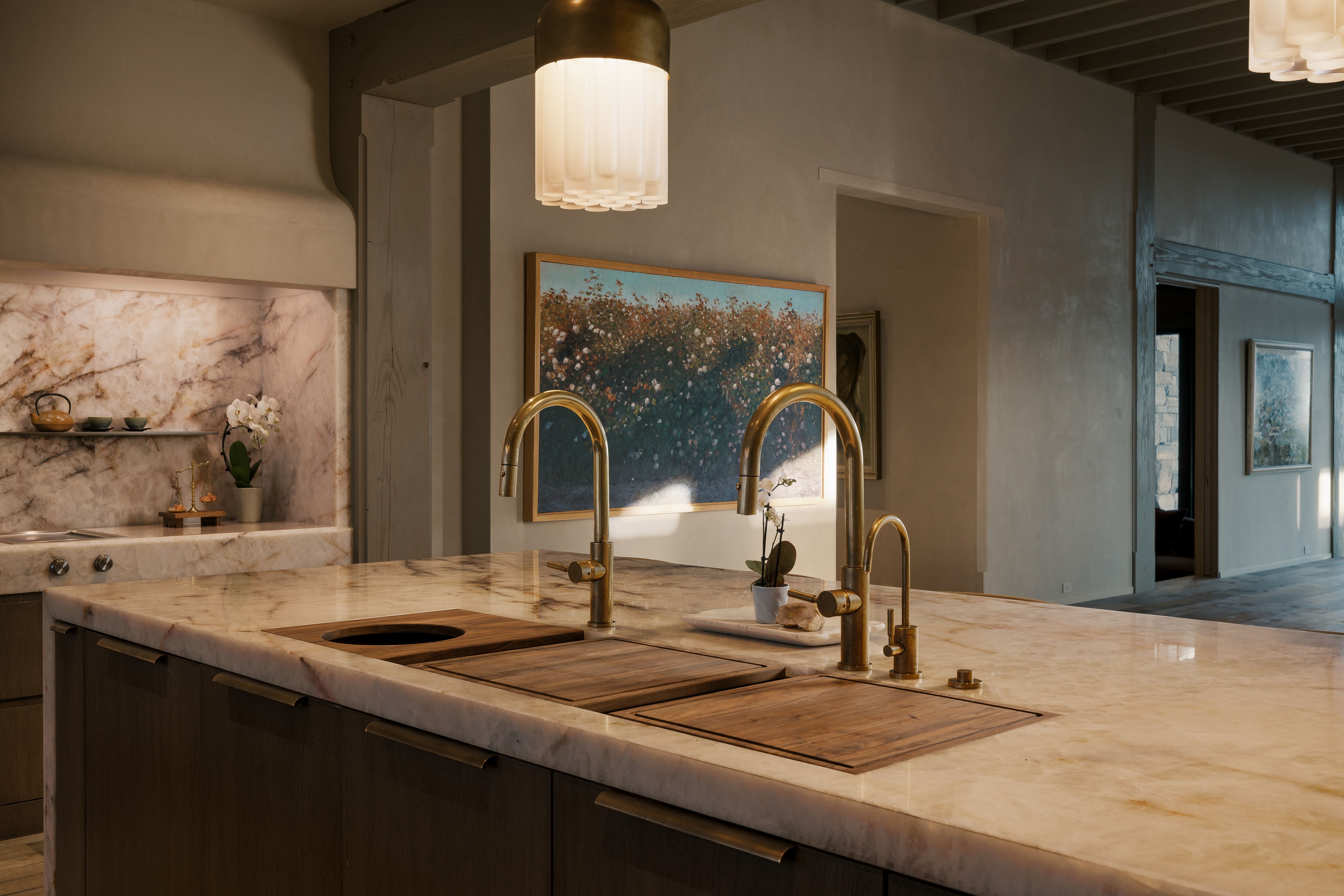 Kitchen island with integrated wooden cutting boards, a secondary round sink, and two brass faucets