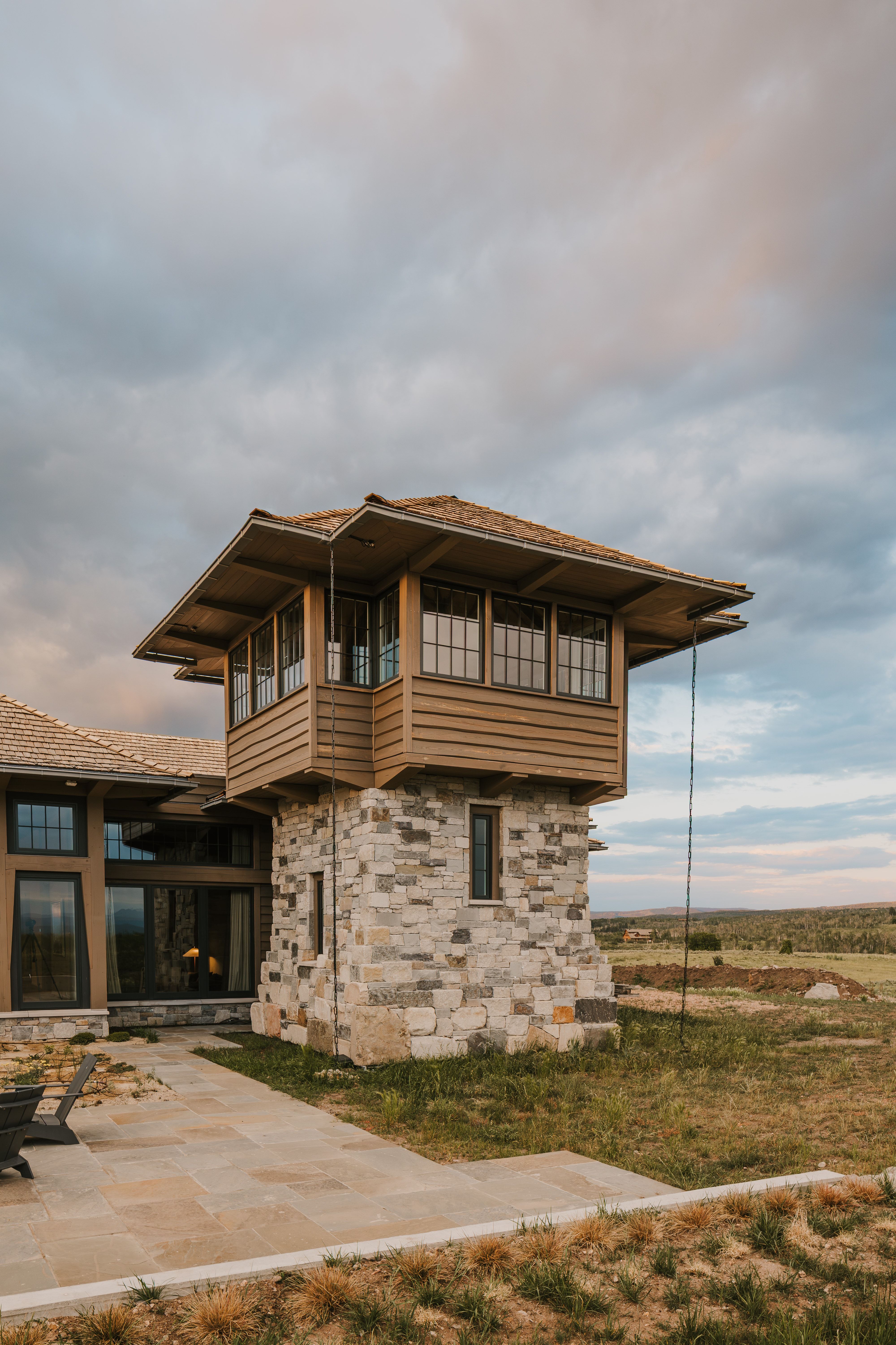 Stone-clad tower with large windows and wood-slat siding