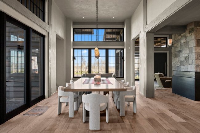 Spacious dining area featuring wood-finish flooring, a contemporary chandelier, and expansive windows