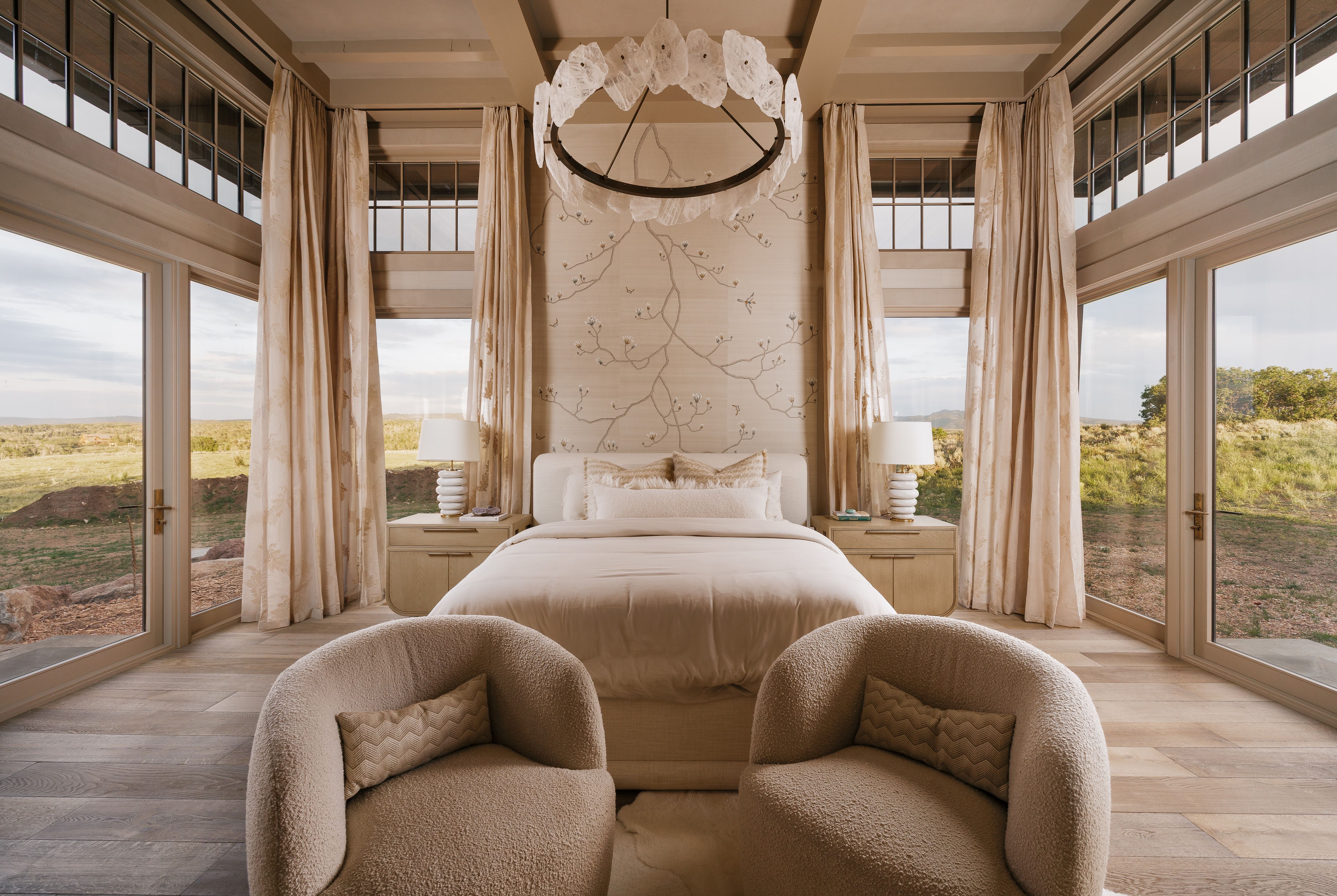 Floor-to-ceiling windows flank a central bed, showcasing extensive outdoor scenery