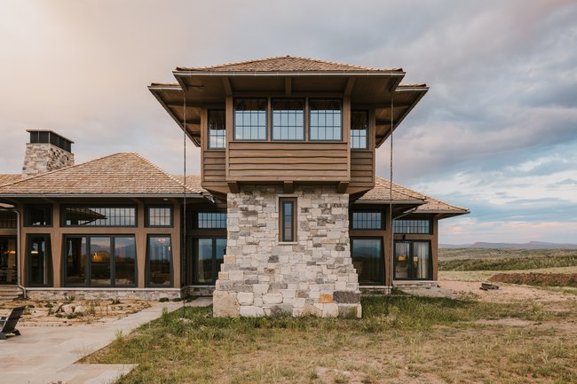 Custom-built residence featuring a stone and wood siding exterior with expansive window walls