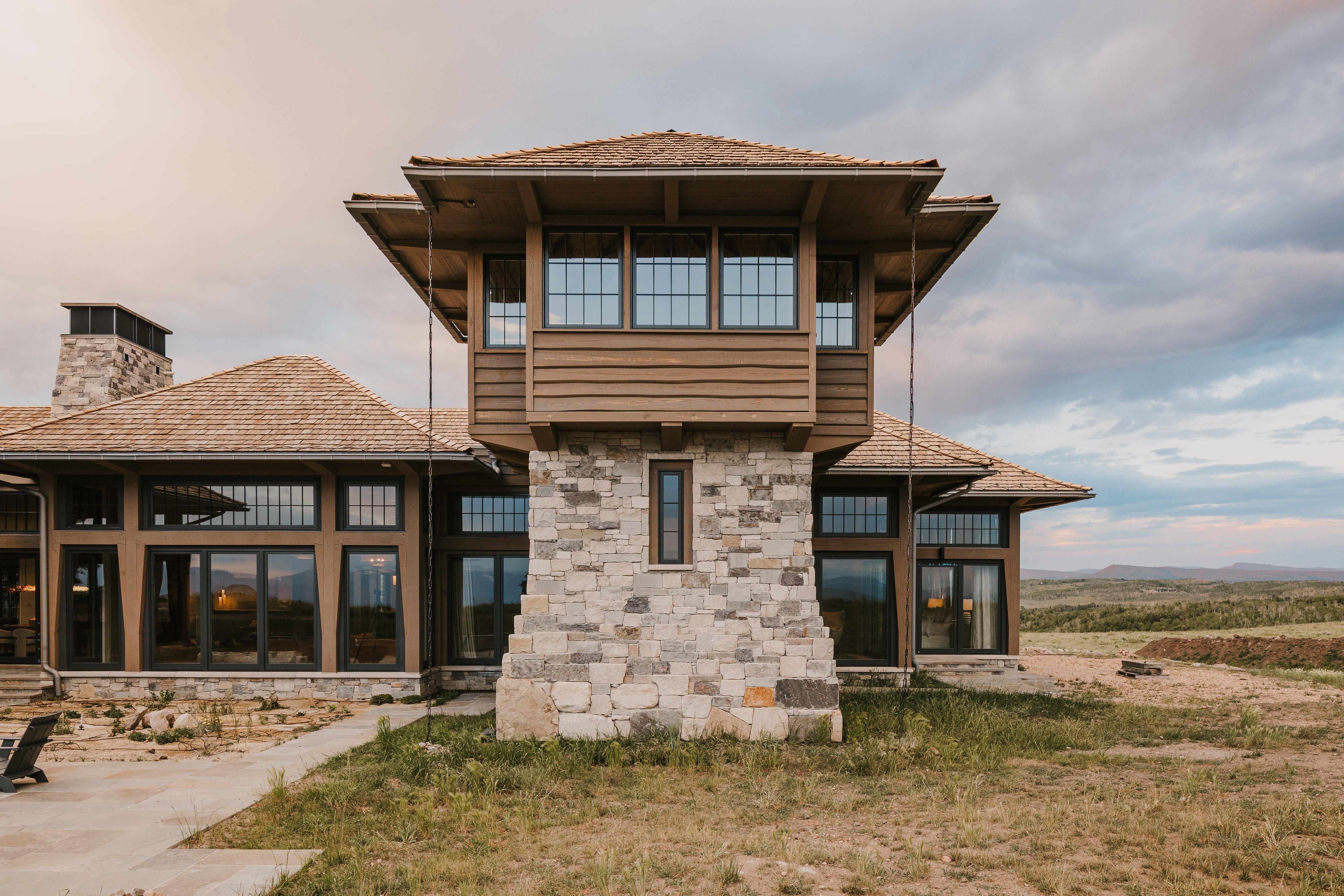 Architectural stonework exterior featuring a distinct tower structure with multi-pane windows