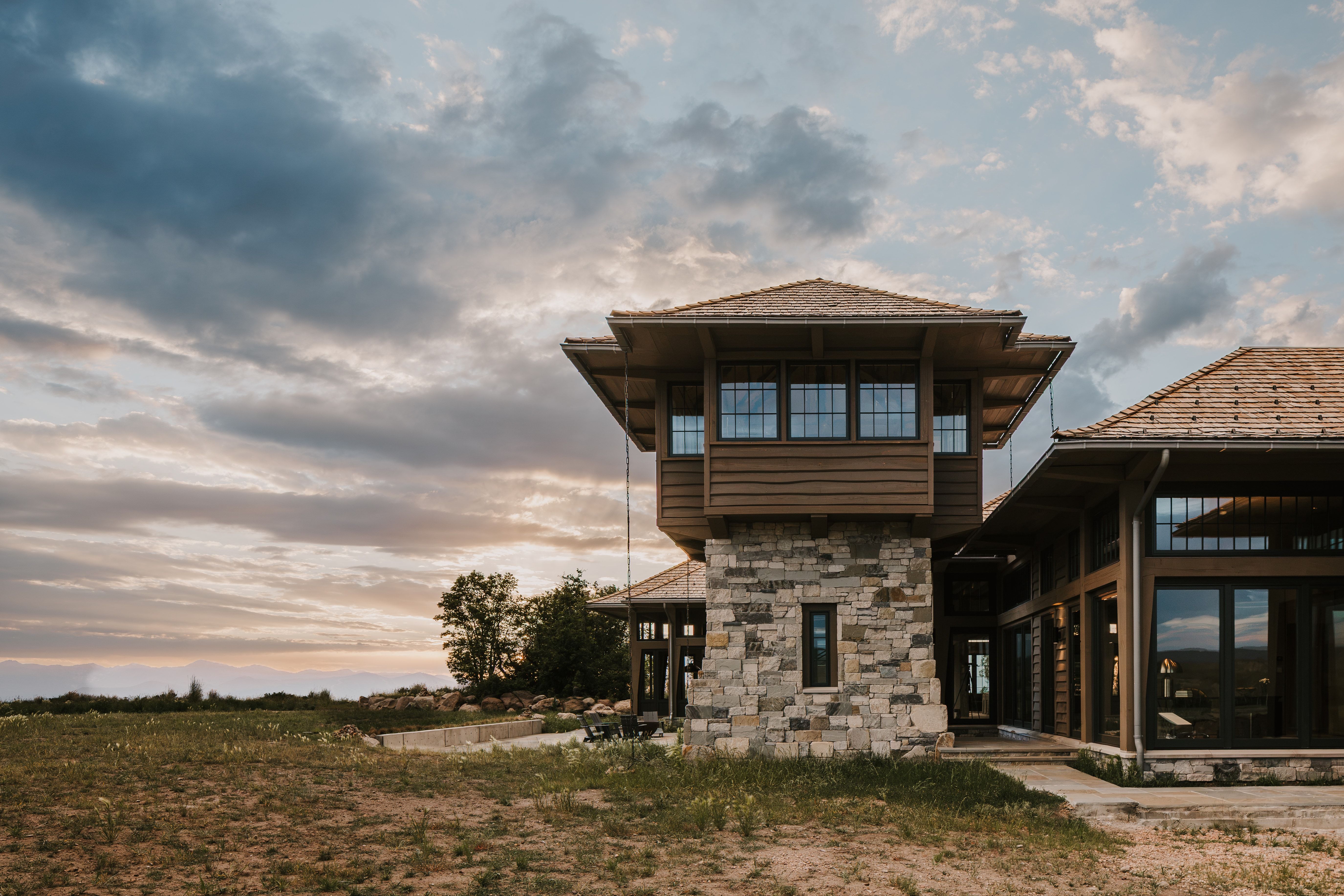 Stone and wood-clad exterior featuring a prominent tower with multi-pane windows