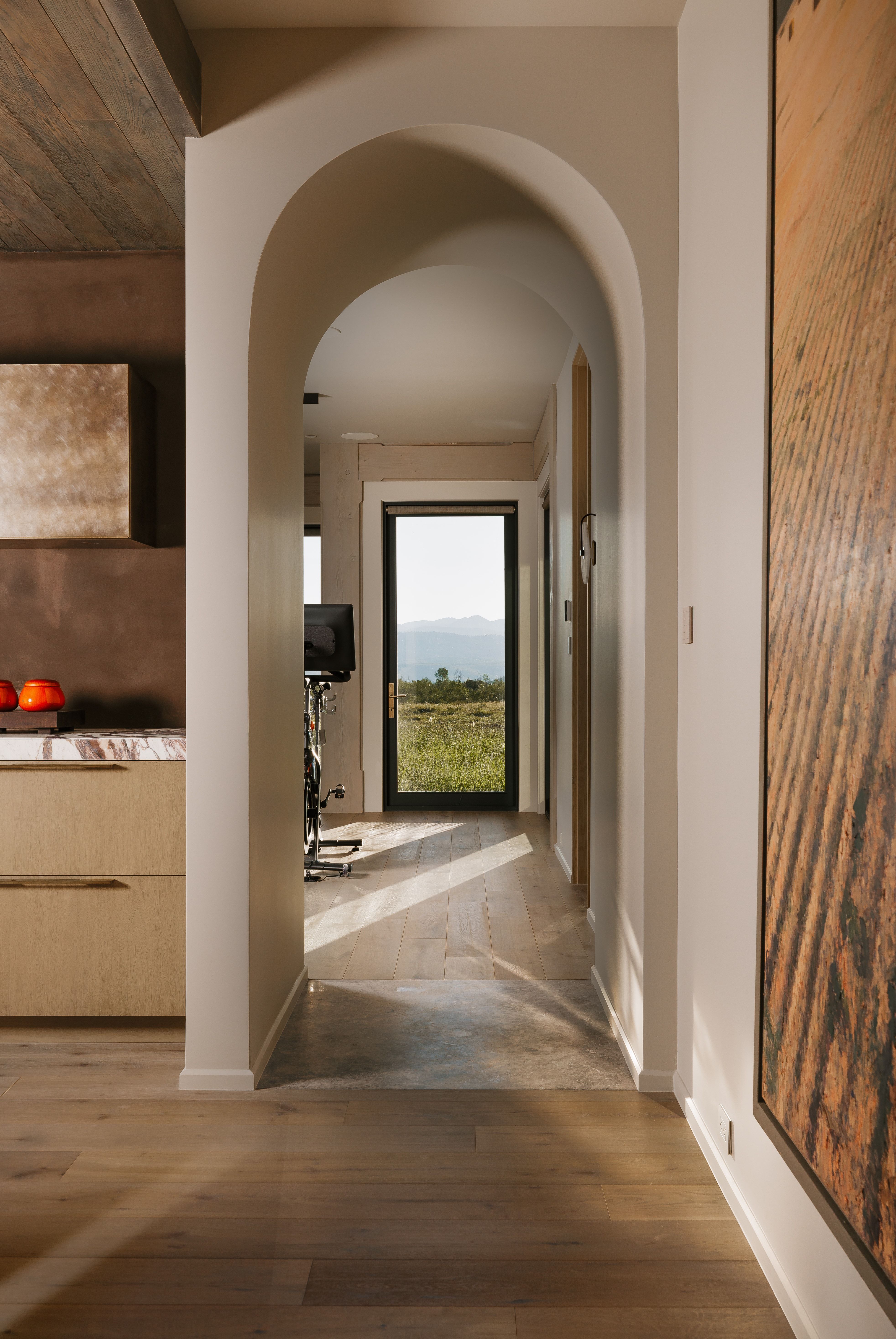 Arched entryway featuring wood-finish flooring, a wood-paneled ceiling, and a distant outdoor landscape