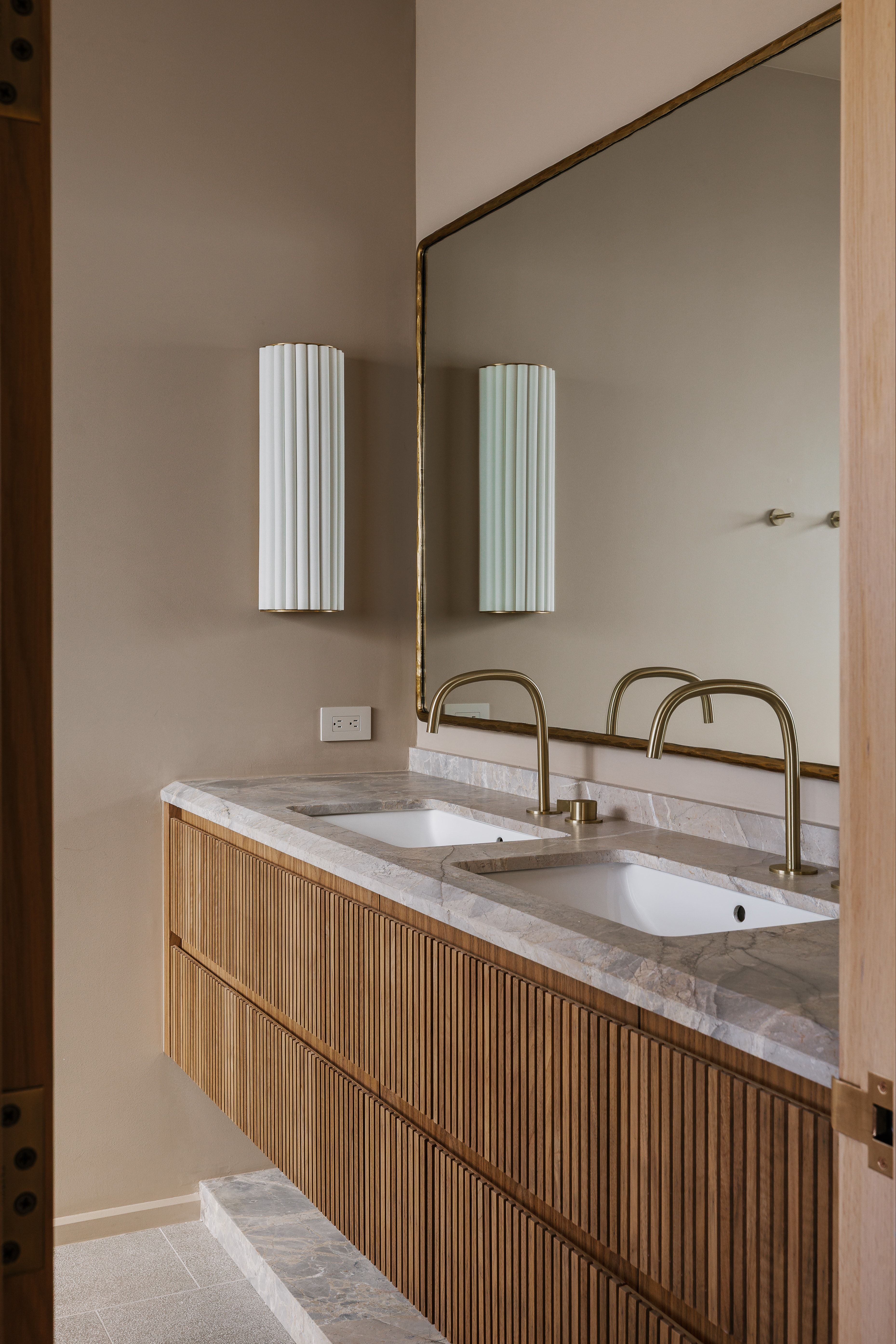 Dual undermount sinks with brass faucets set into a stone vanity top