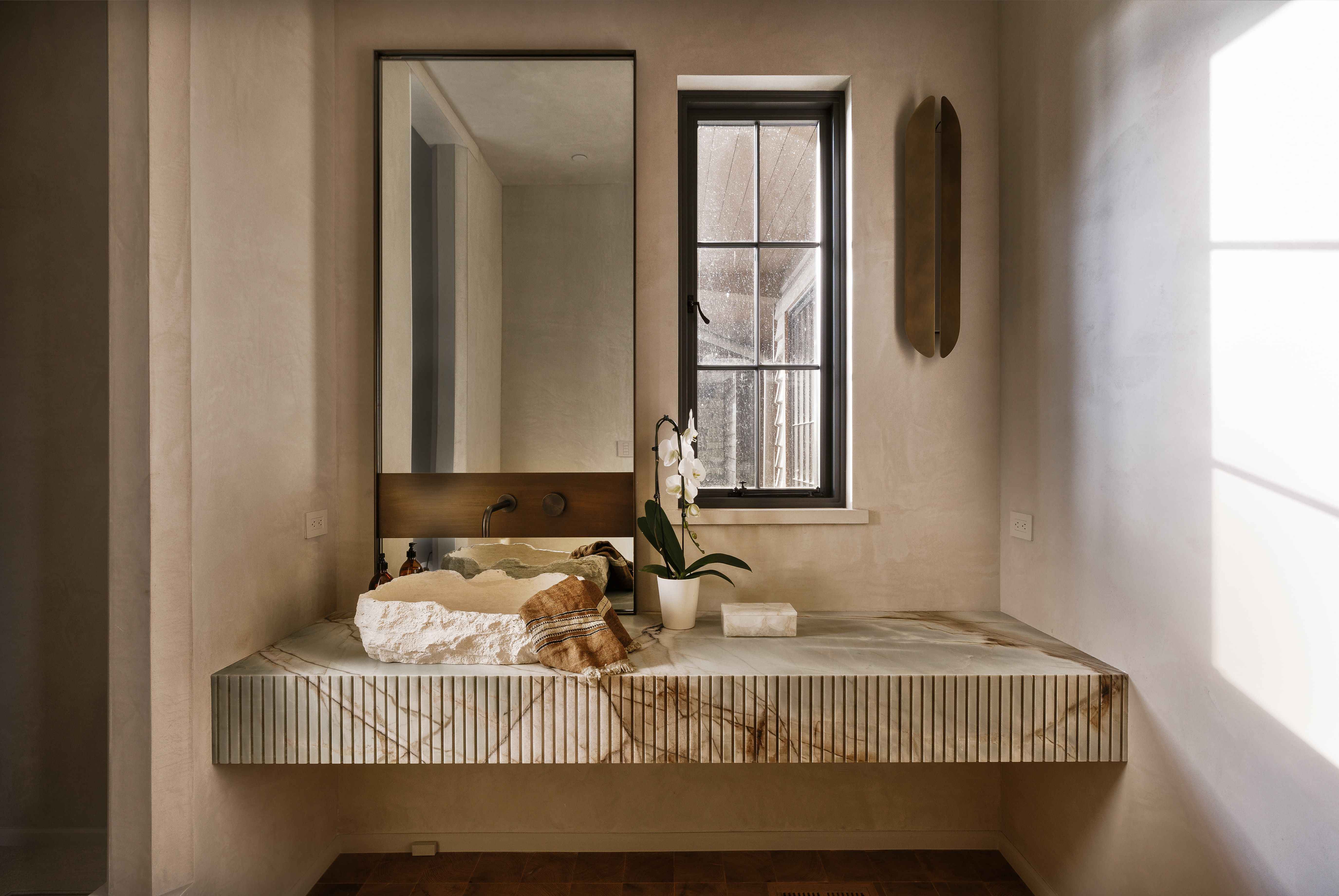 Floating vanity featuring a natural stone vessel sink and a wall-mounted faucet
