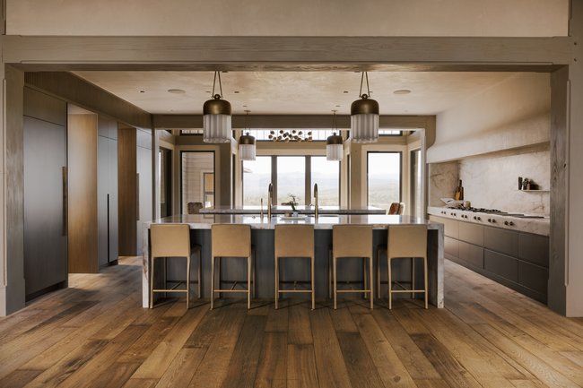 Gourmet kitchen featuring a large central island with seating, integrated appliances, a professional-grade range, wood-finish flooring, and expansive windows
