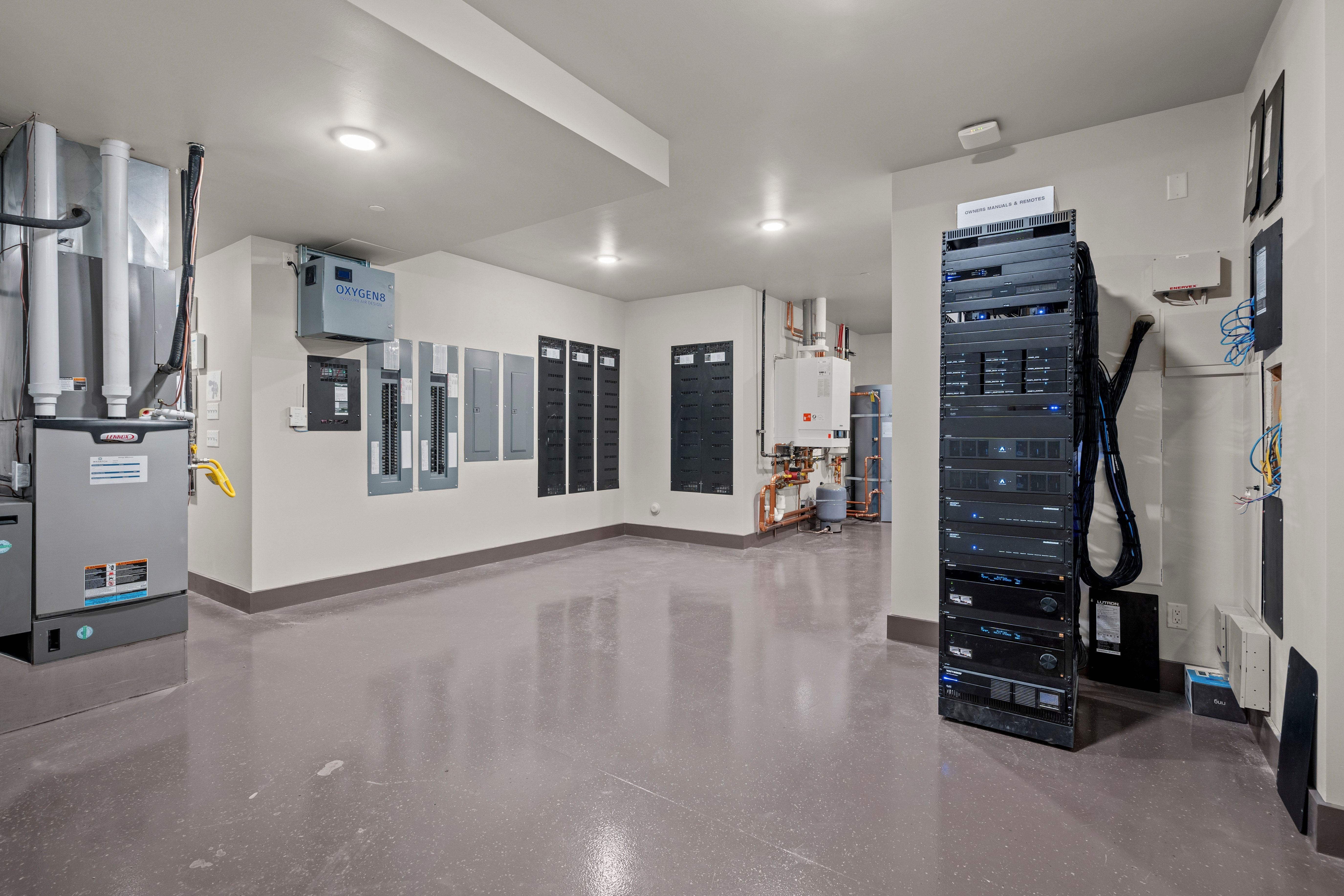 Utility room featuring multiple electrical panels, an HVAC system, and a robust network server rack