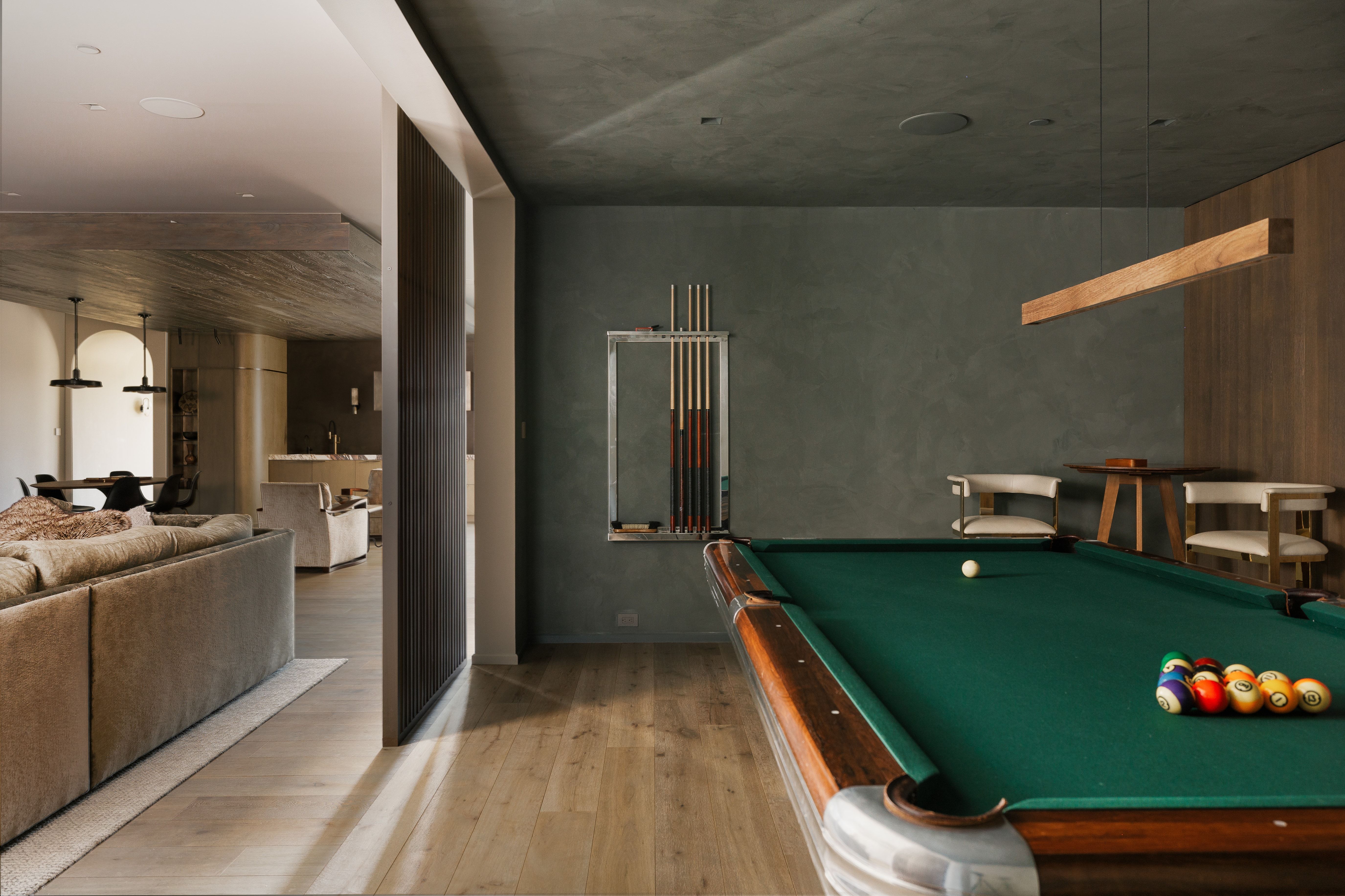 Game room featuring a billiard table with green felt, wood-finish flooring, textured wall finishes, and a contemporary linear pendant light fixture