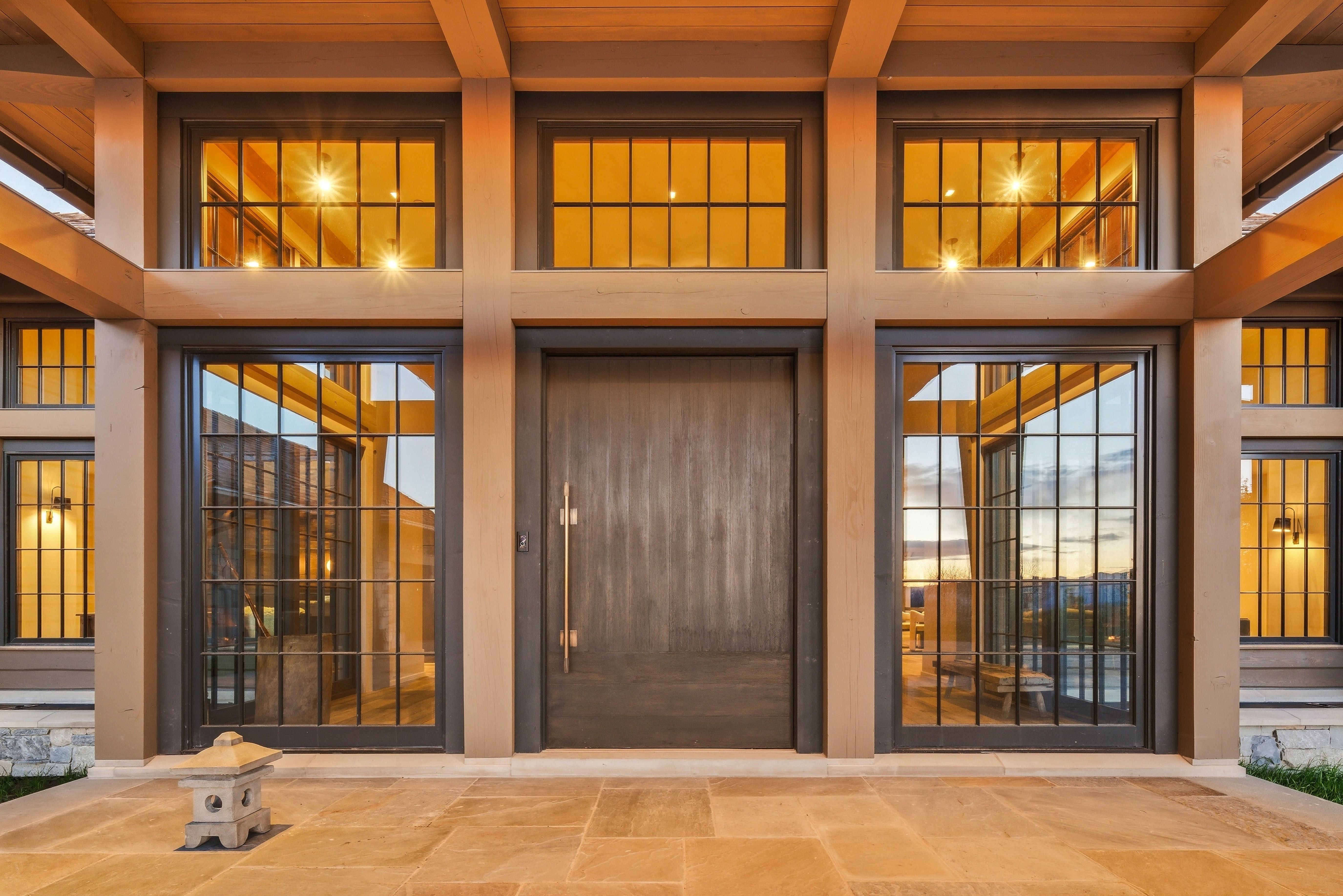 Contemporary entry featuring a wood-grain door flanked by grid-paneled windows and transom windows