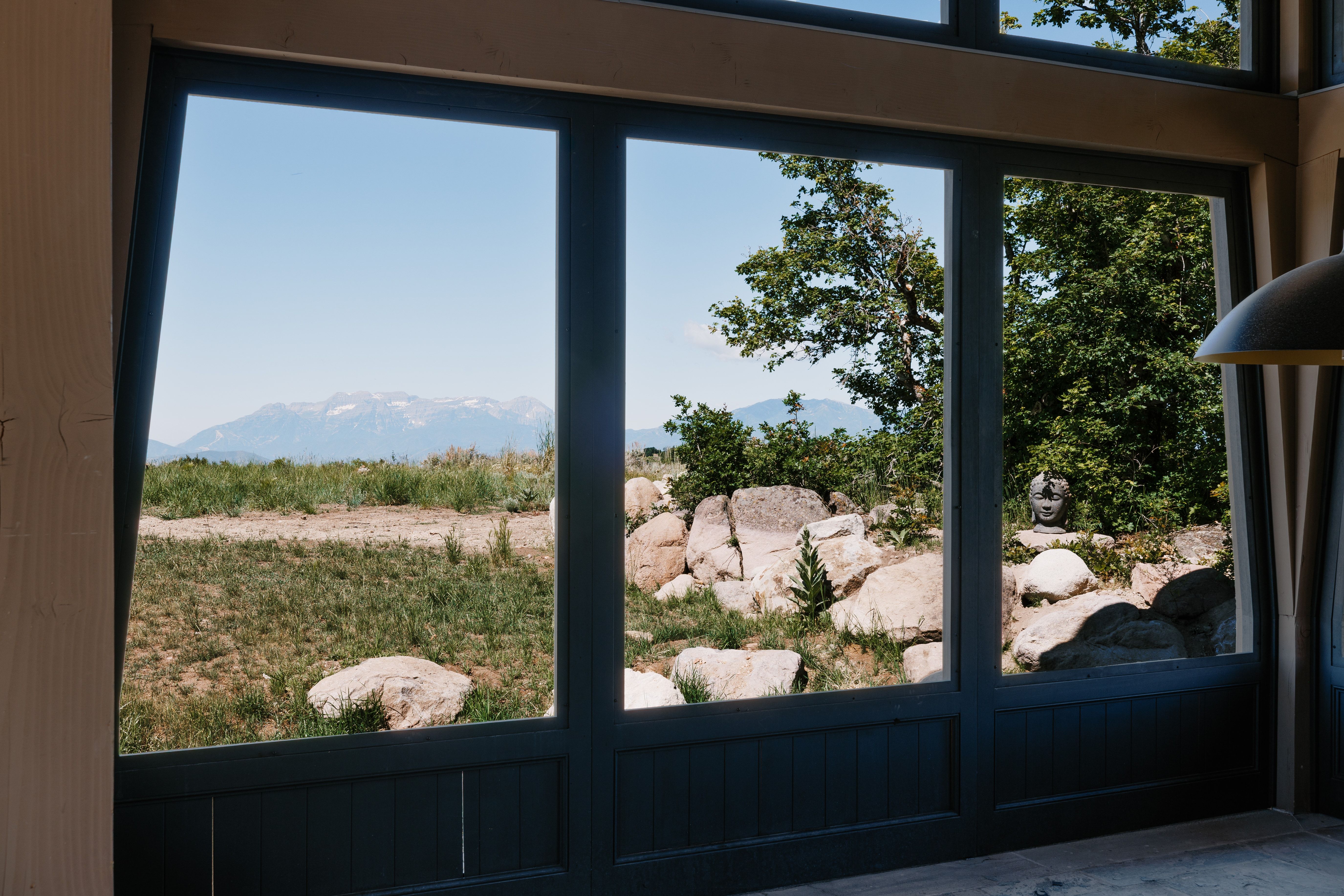 Expansive multi-pane windows with dark frames, offering mountain and natural landscape scenery