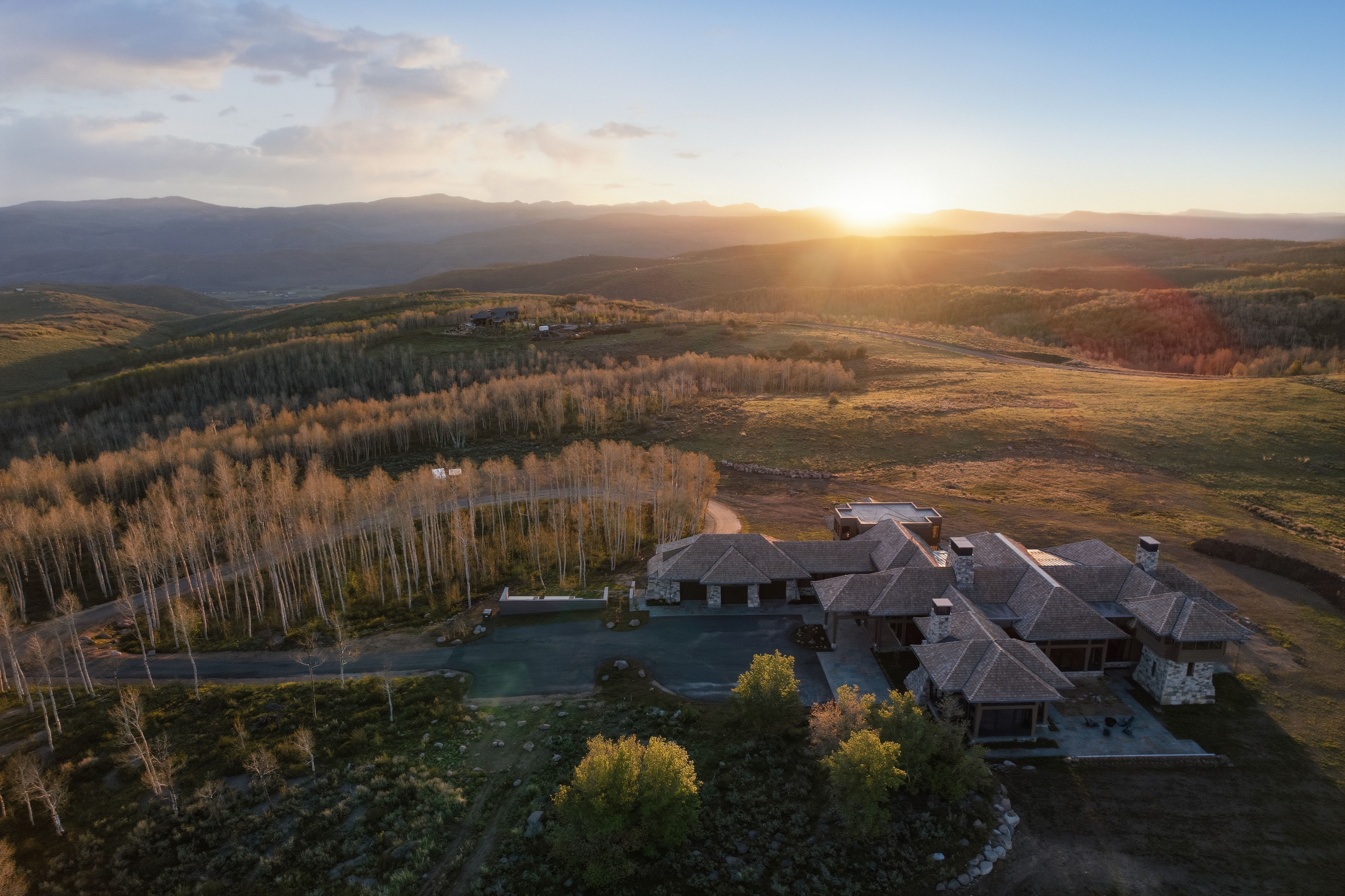 Expansive property featuring a multi-wing residence with a stone and wood exterior, multiple chimneys, and a shingled roofline