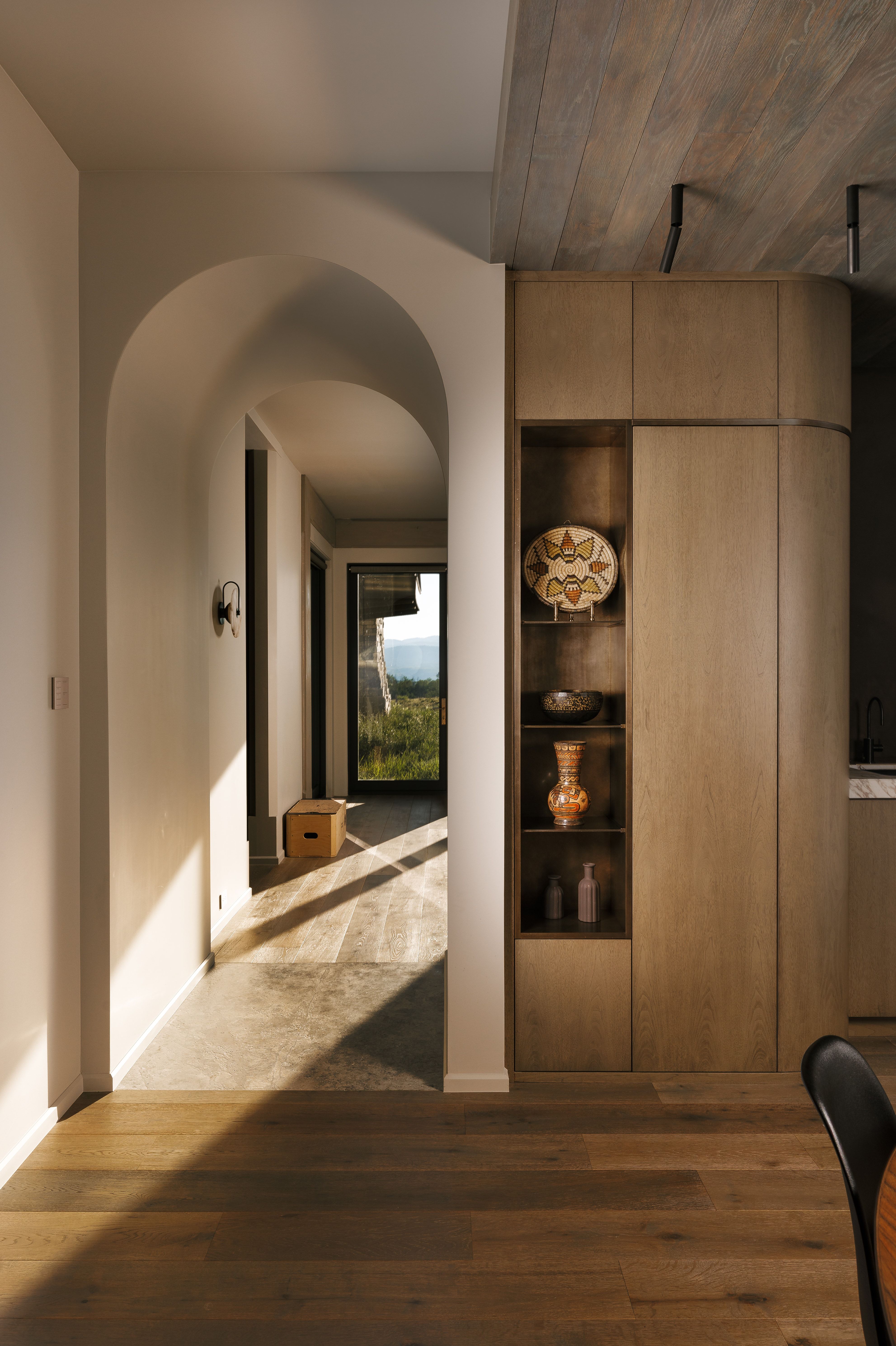Hardwood flooring extending to an arched hallway with recessed lighting