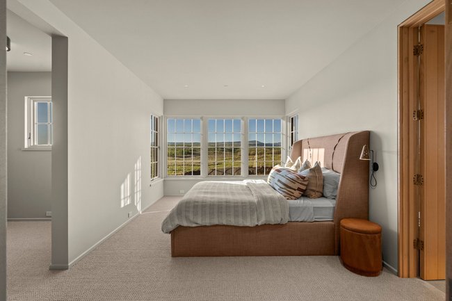 Bright interior space featuring multiple windows with grid detailing, plush carpeting, recessed lighting, and a solid wood bifold door