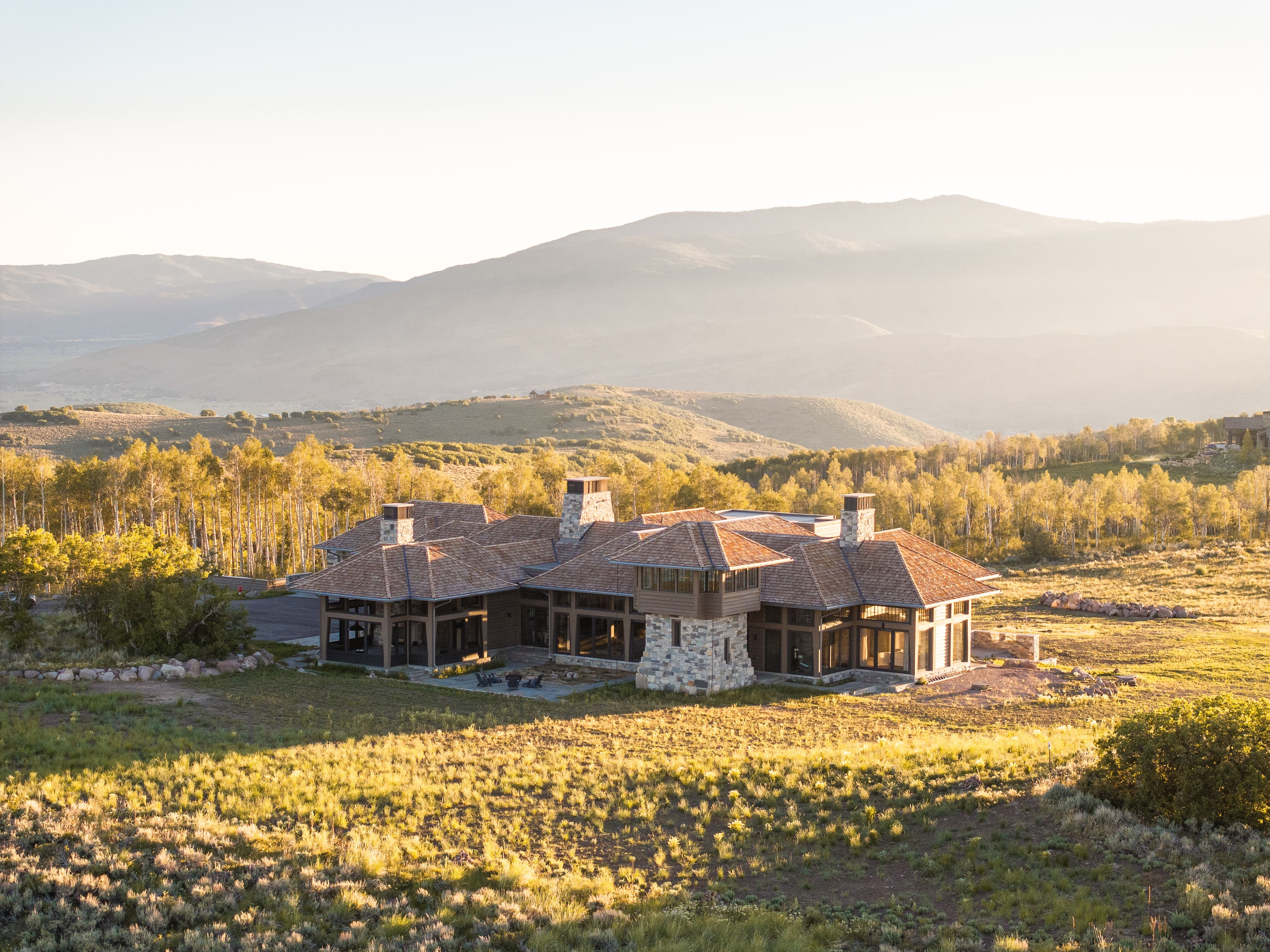 Expansive custom residence featuring multiple gabled rooflines, stone and wood siding, and numerous large windows