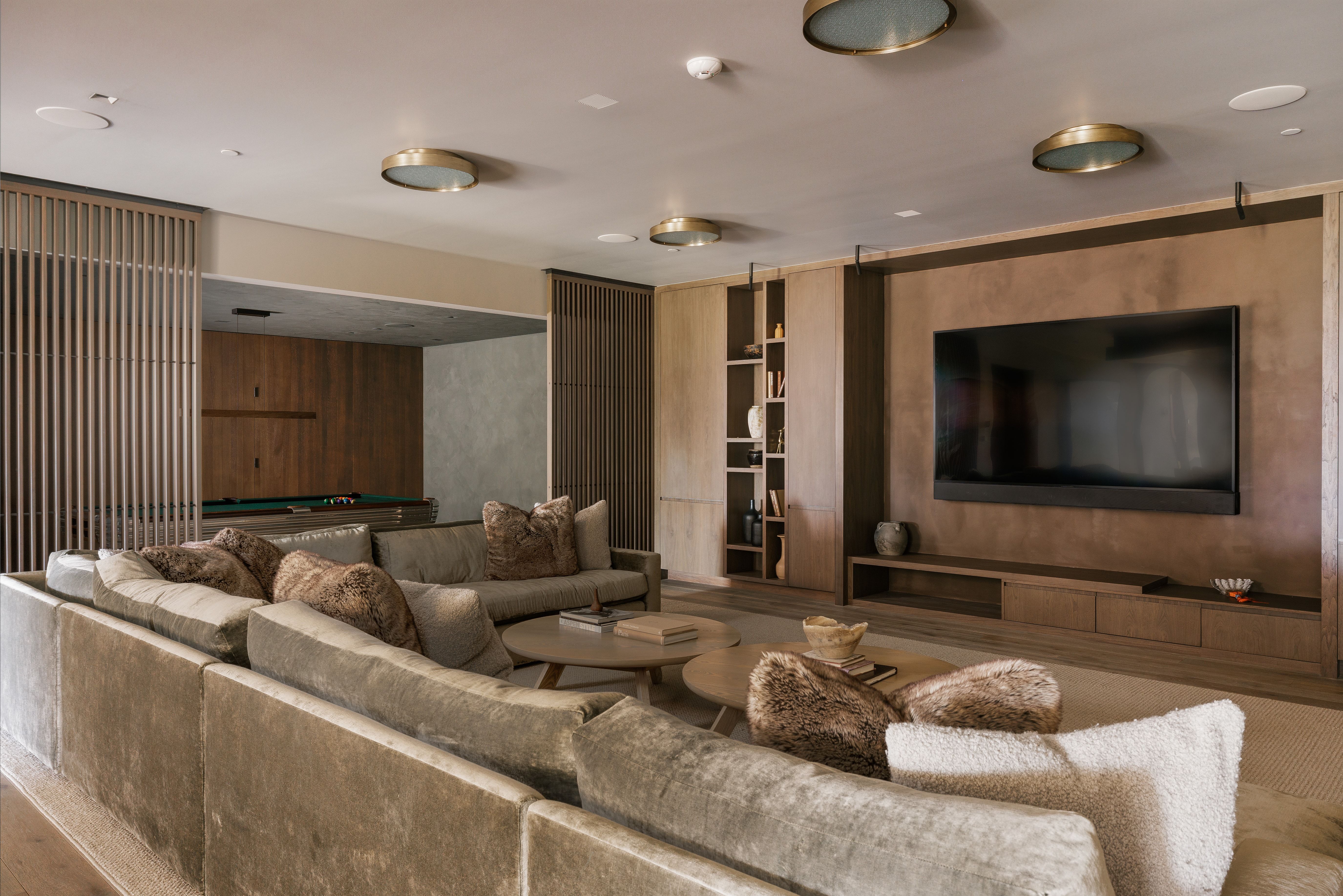 Contemporary living space featuring a large wall-mounted television, a built-in media console with storage, and integrated shelving