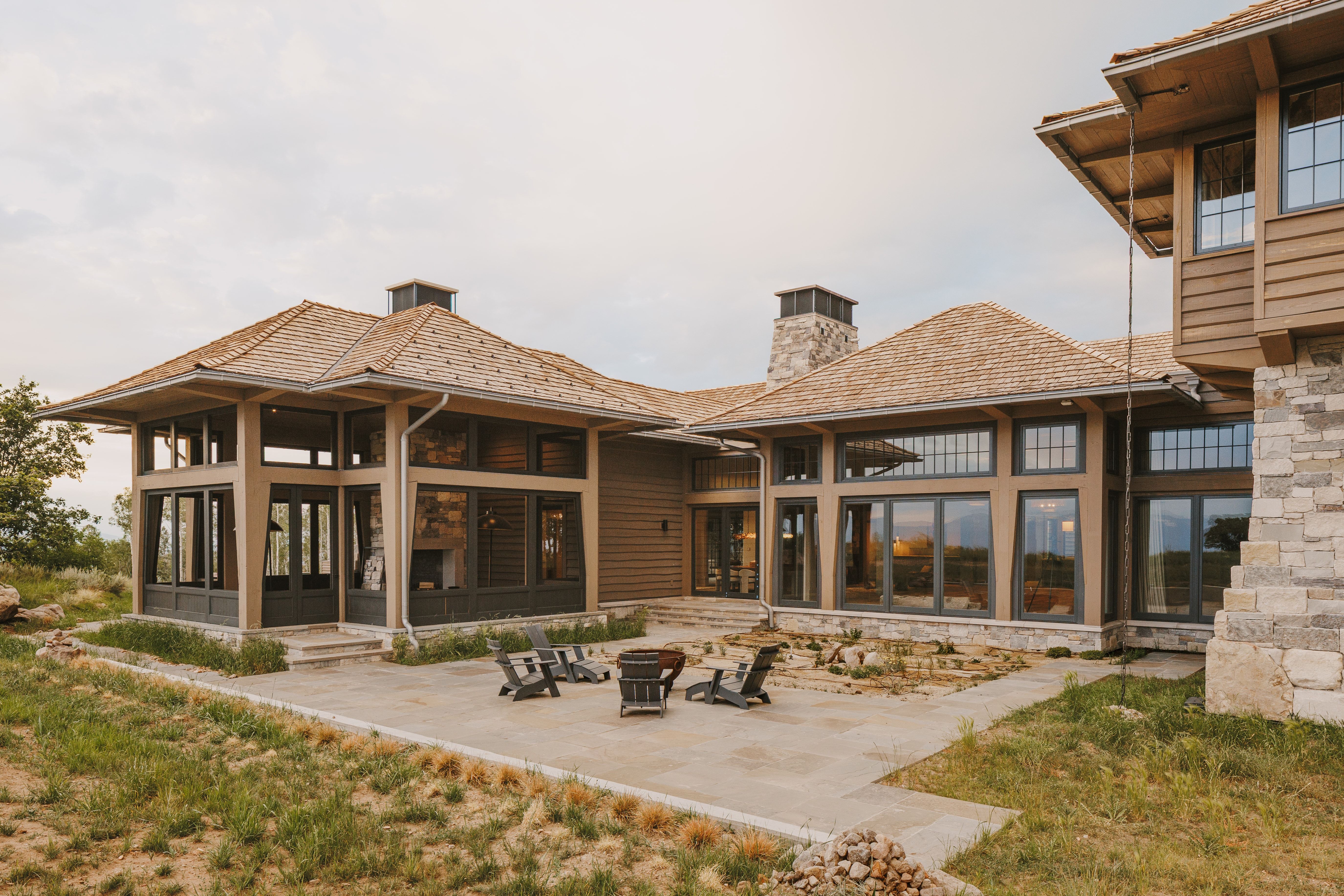 Expansive outdoor patio featuring a fire pit area, natural stone accents, and a stone-clad chimney