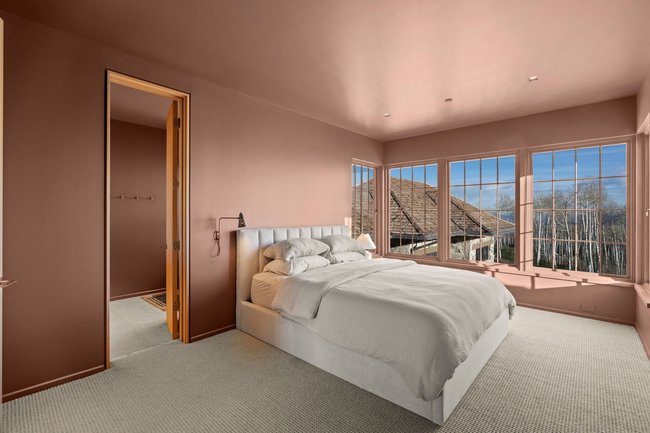 Expansive windows framing exterior scenery, recessed lighting, wall-mounted sconce, and neutral carpeting