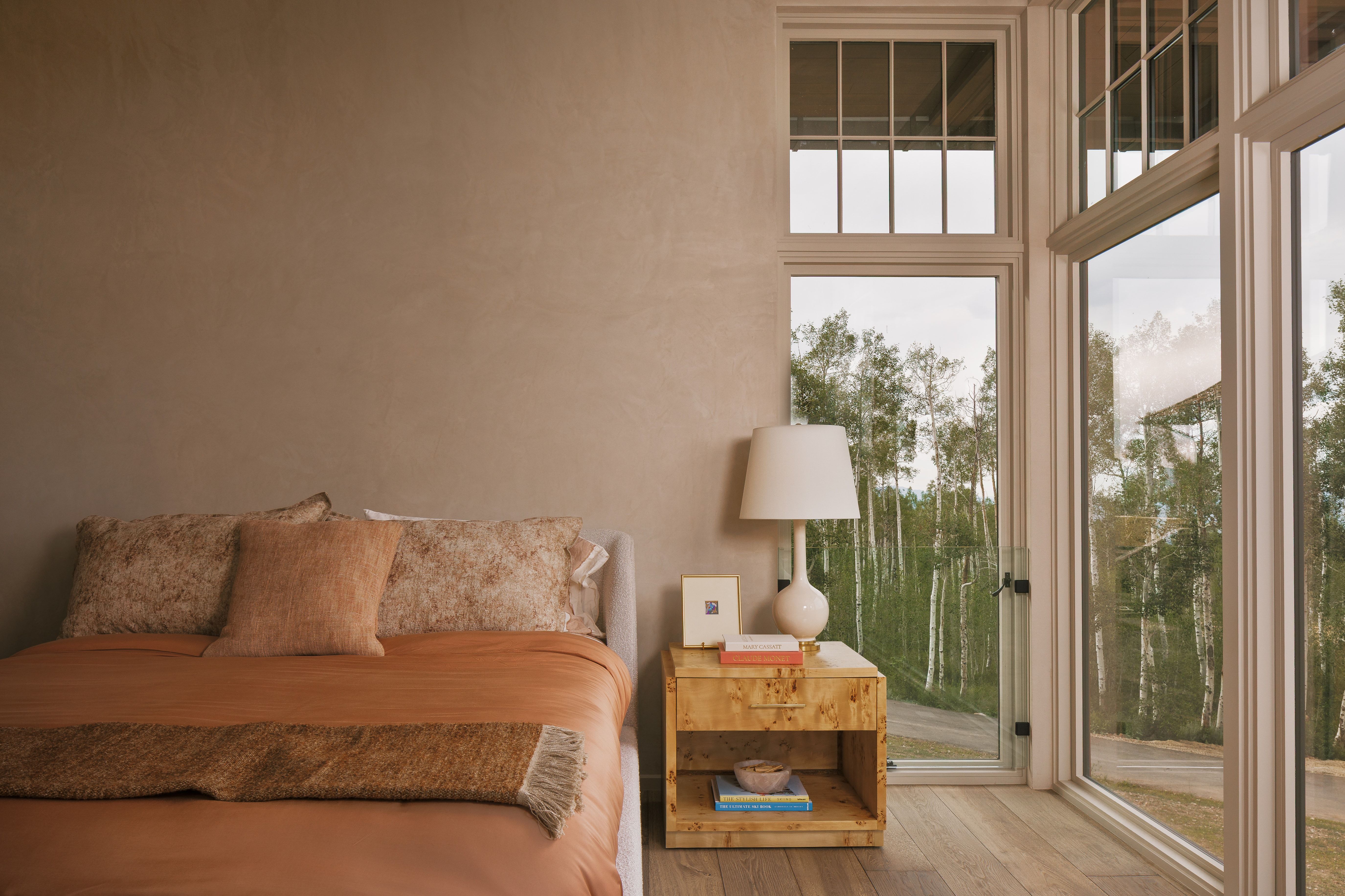 Large pane windows with white trim, wood-finish flooring, textured wall finish, and a built-in wood nightstand with open shelving