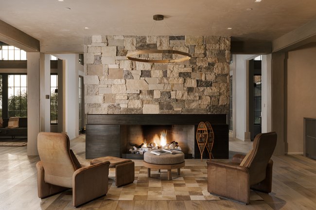 Stone-clad fireplace with a recessed hearth, dark wood mantel, and integrated wood storage