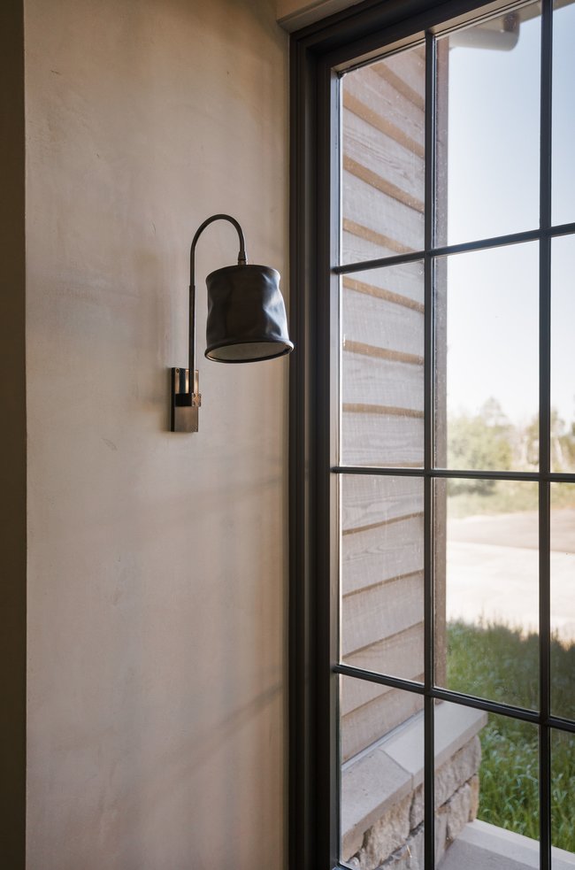 Contemporary black sconce with a curved arm and cylindrical shade
