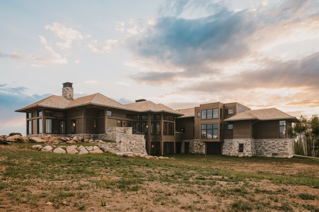 Contemporary multi-level residence featuring extensive natural wood siding and varied stone accents