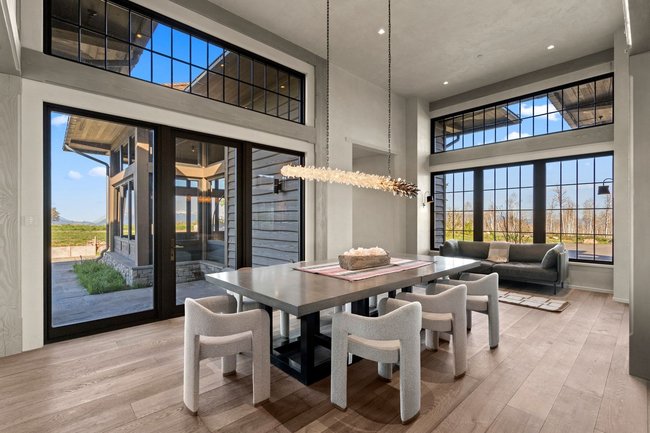 Spacious dining area featuring wood-finish flooring, a contemporary chandelier, and high ceilings
